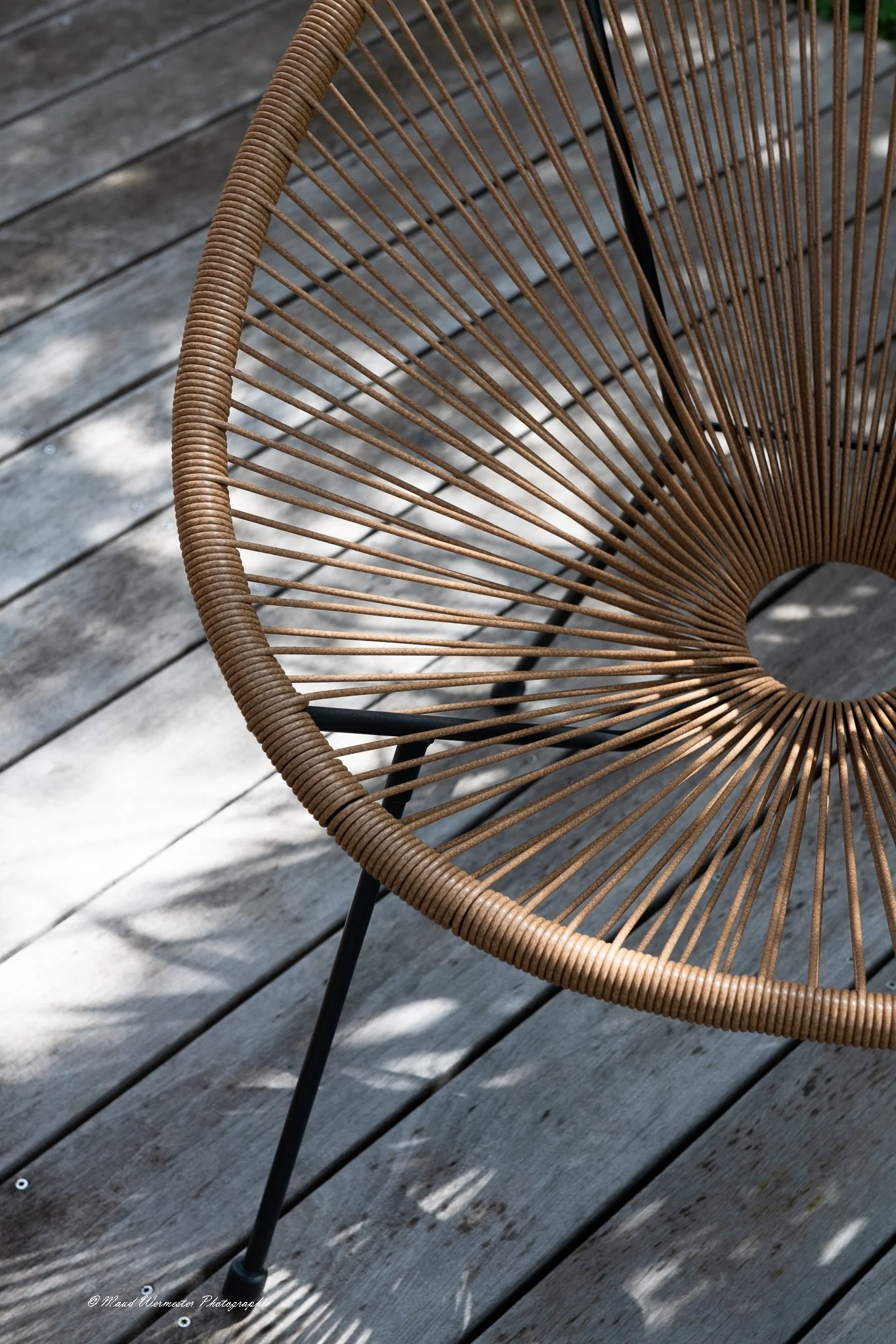 Chaise en rotin au design en arc avec un siège en rayons, posé sur un plancher en bois. immobilier annecy, realestate annecy, Annecy photograhe, mobilier photographie