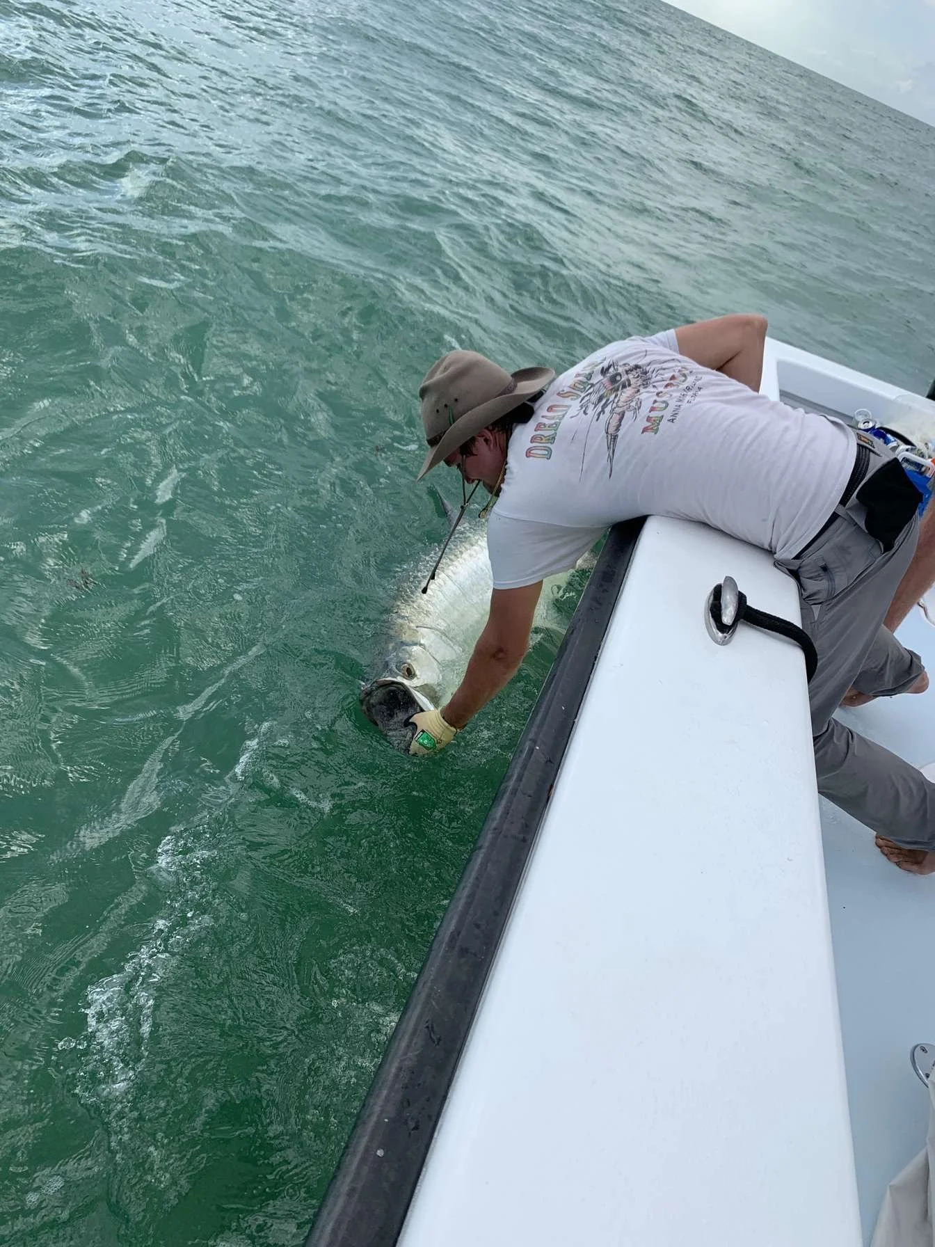 A person on a boat holding a large fish just below the water surface.