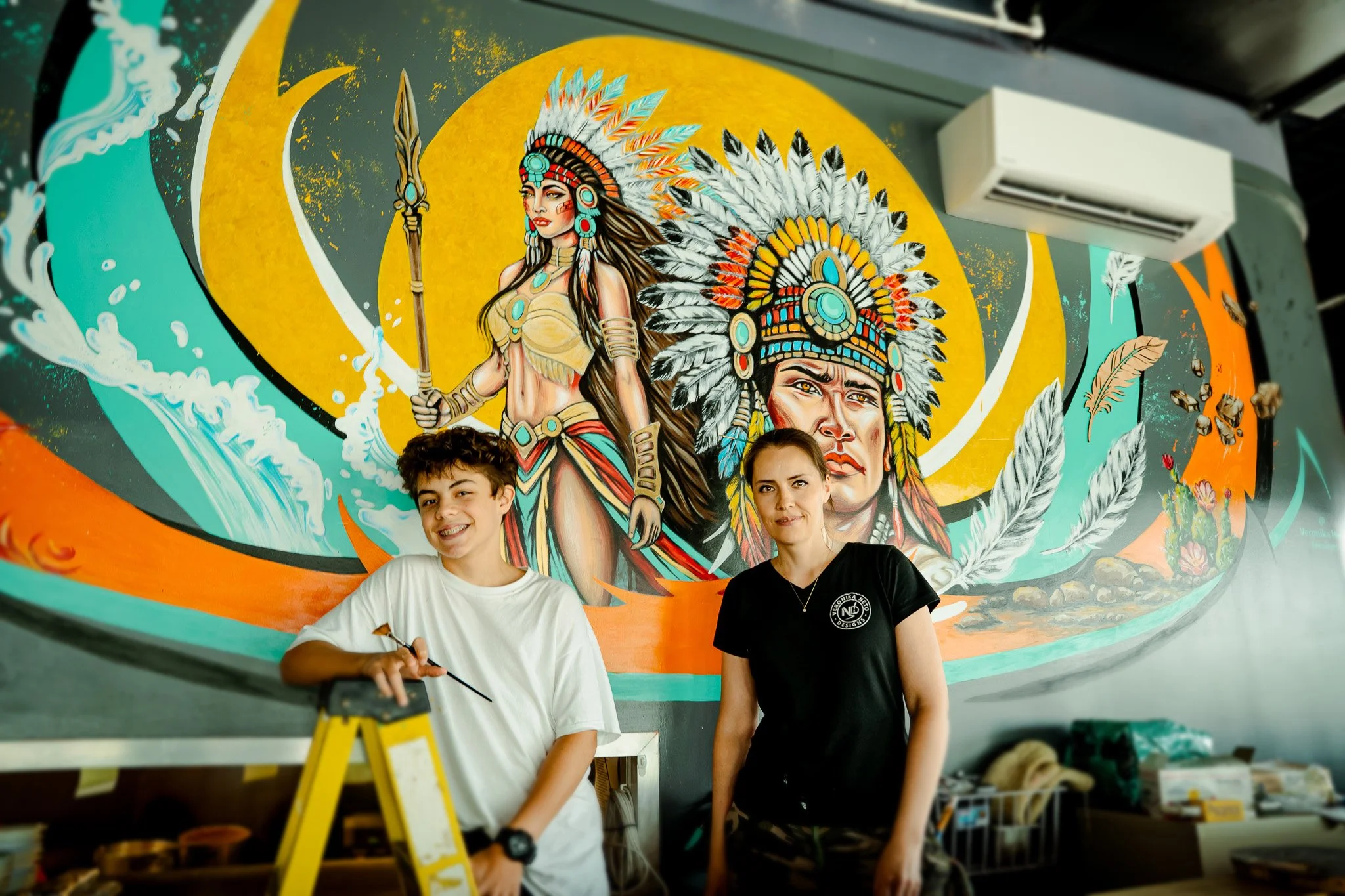 Veronika Neto next to native mural at a restaurant establishment in Pittsburgh