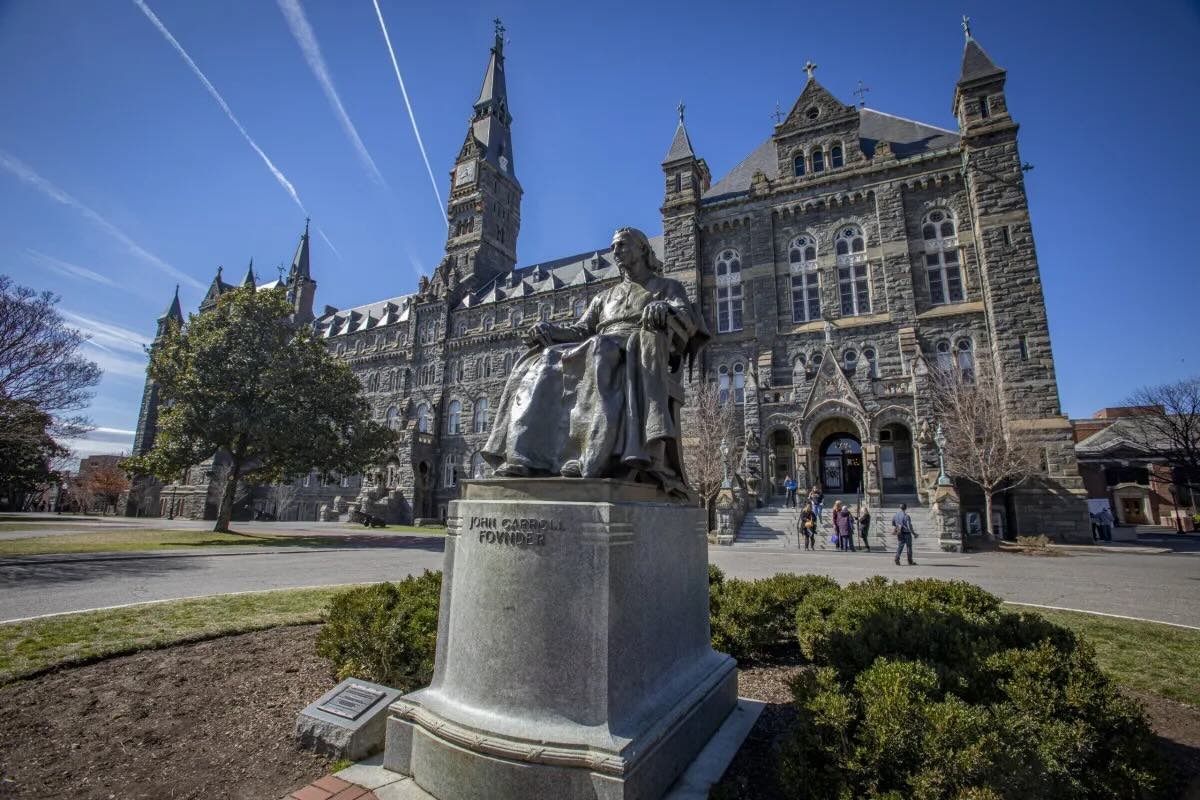 John Carroll statue in front of Healy Hall at Georgetown University with students walking on campus