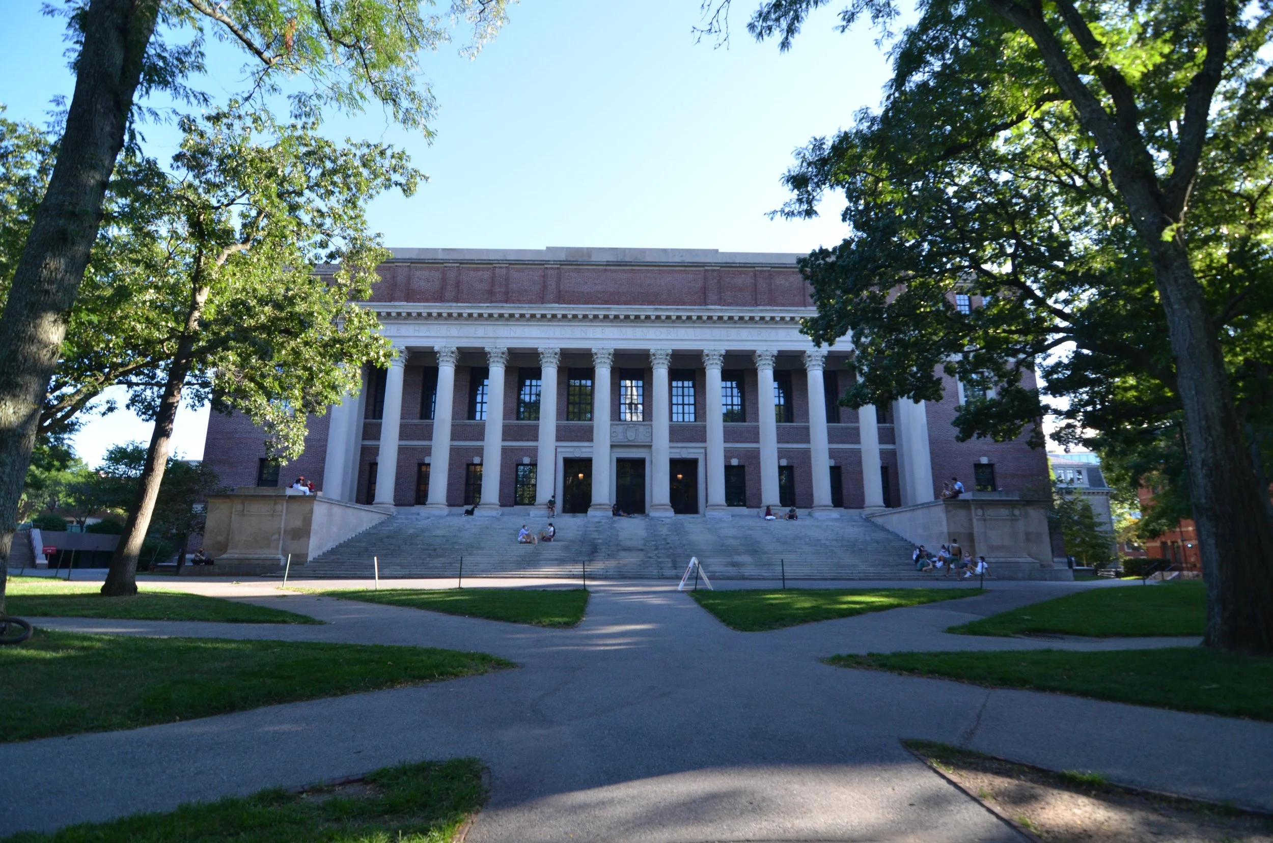 Harvard Widener Library with columns and steps in Harvard Yard with students sitting outside