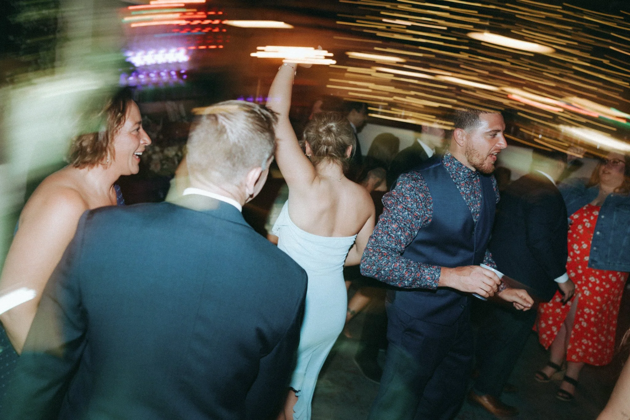 People dancing and enjoying a party with colorful lights and motion blur.