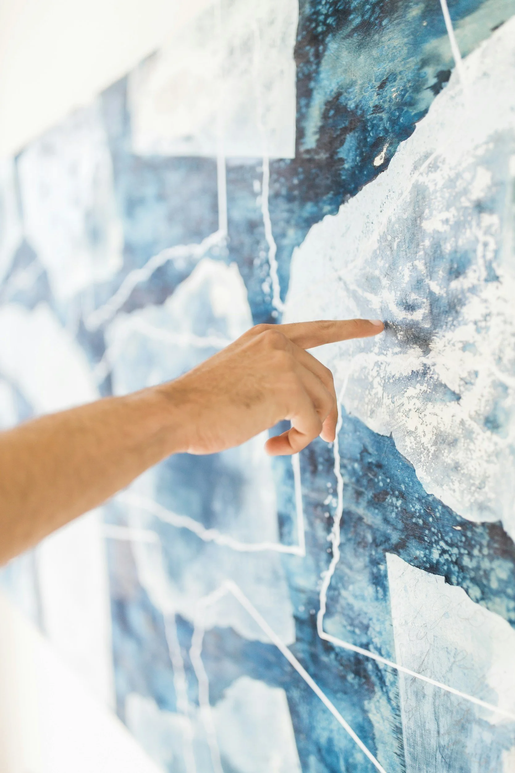 A person's hand pointing to a map of Antarctica.