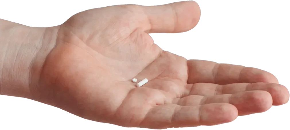 An open human hand holding two pills, one round and one capsule-shaped.