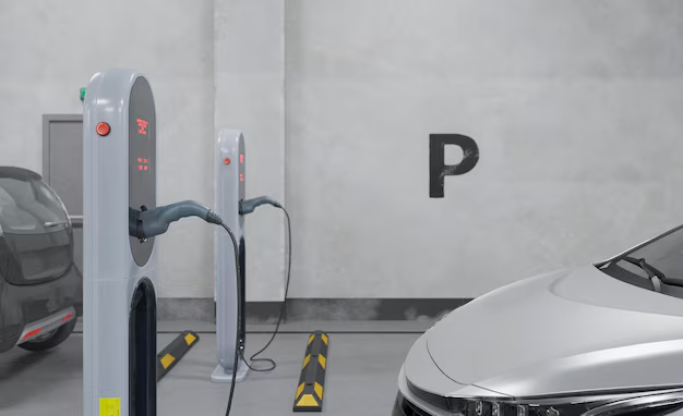 Two electric vehicle charging stations, one actively charging a dark gray car, in a concrete parking garage.