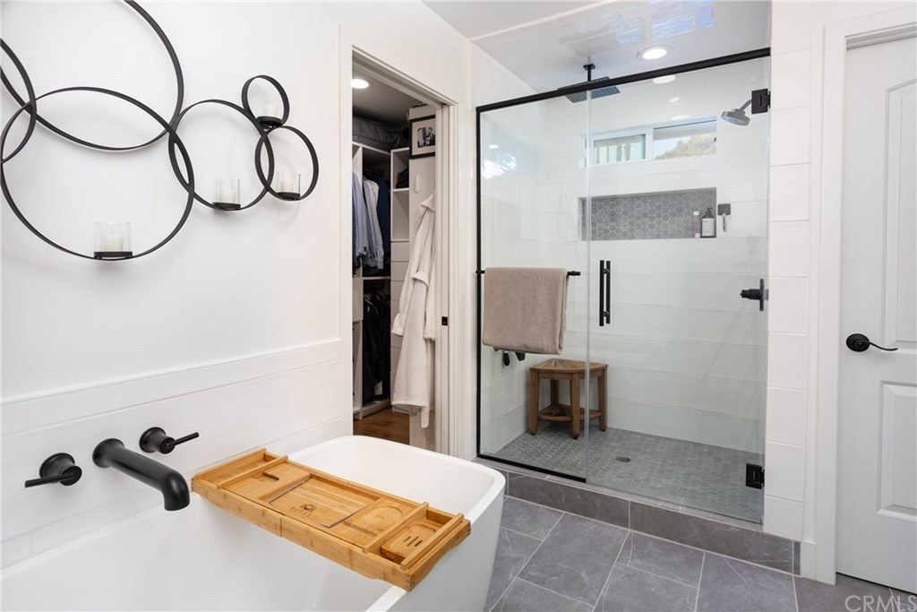 Modern bathroom with white walls, black fixtures, and a glass-enclosed shower with gray hexagon tiles.