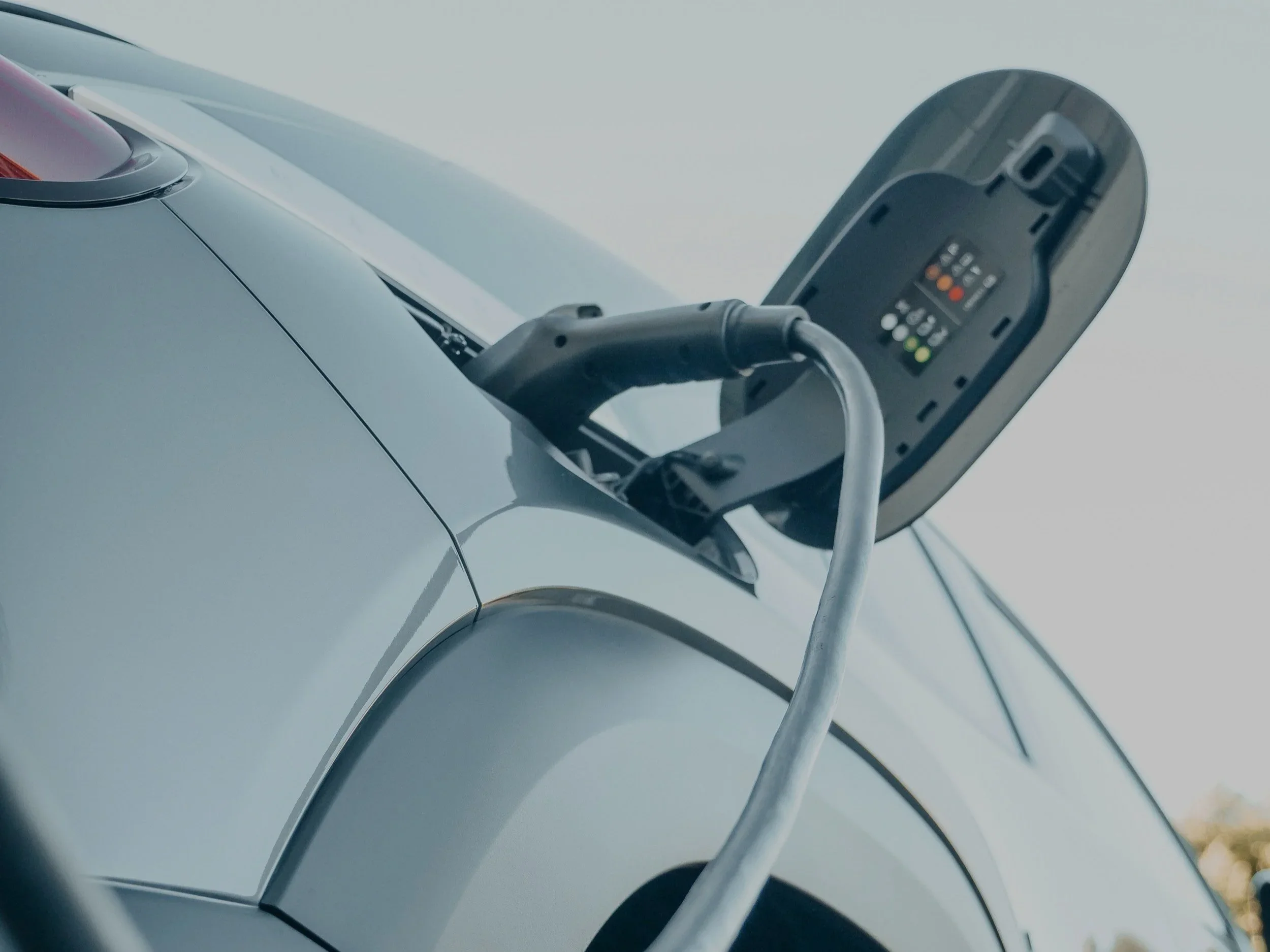 Close-up of a Tesla electric vehicle charging port with charging connector inserted.