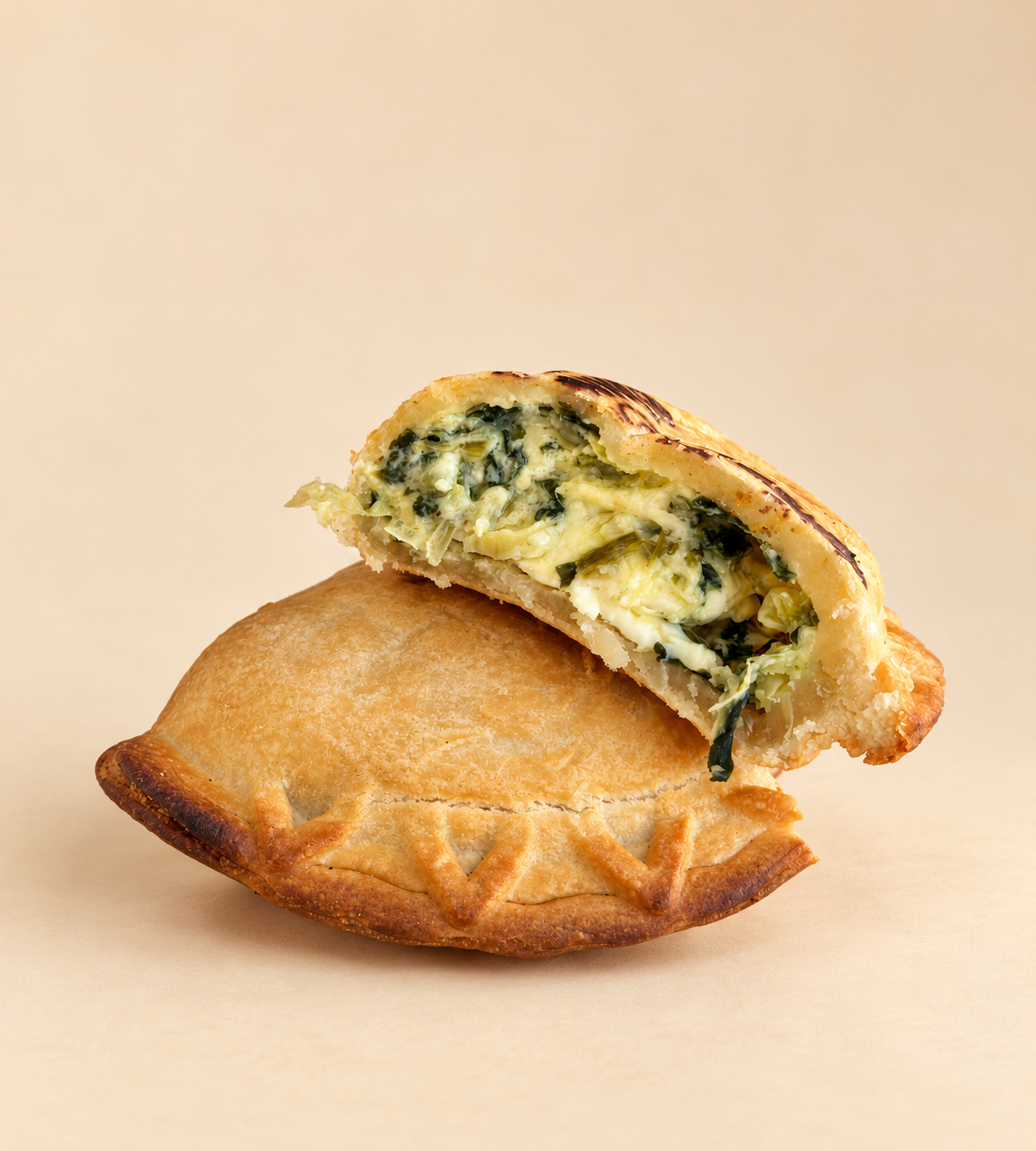 A stuffed pastry cut open to reveal a creamy filling with herbs and vegetables, placed on a background with playful typography.
