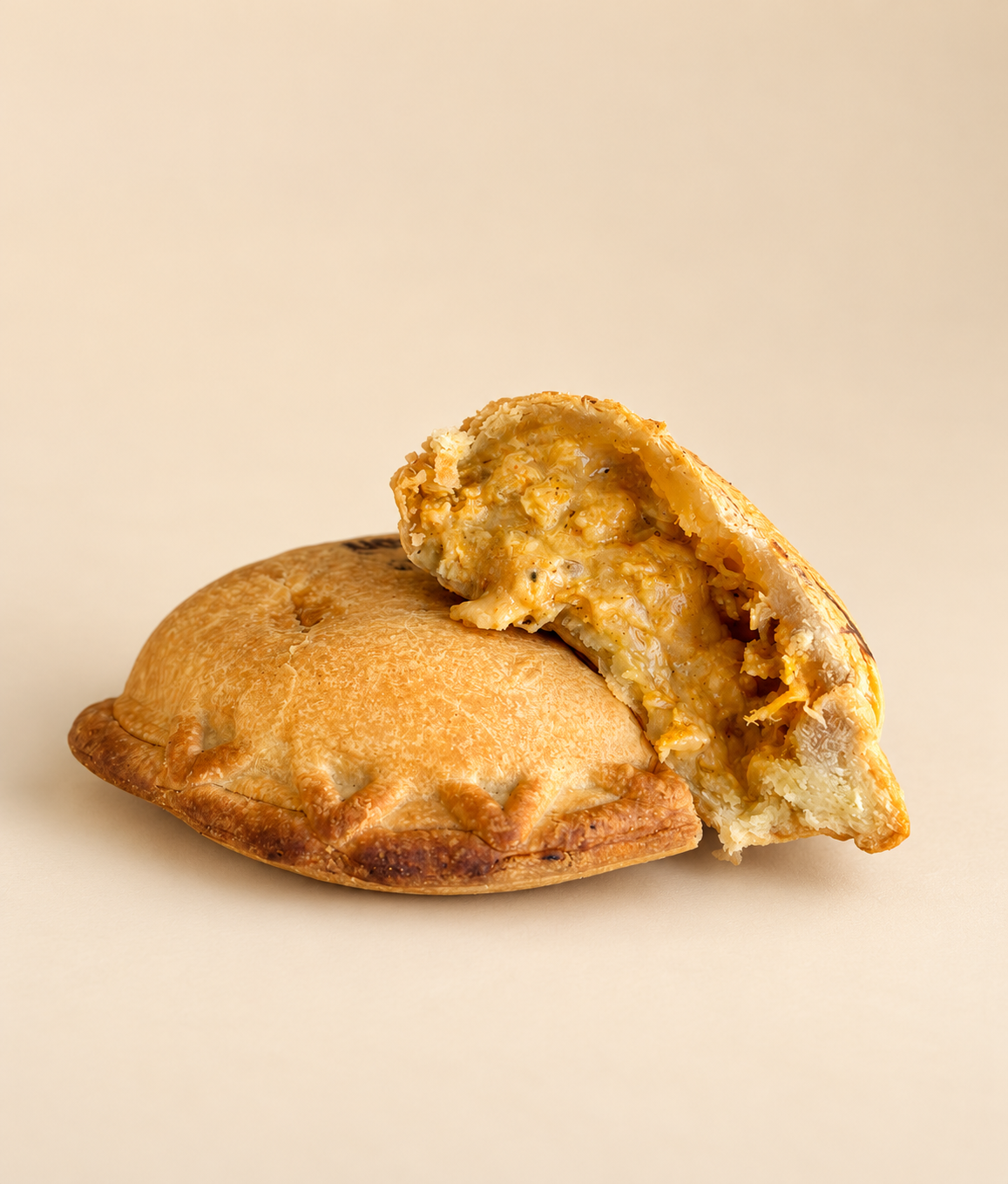 A sliced empanada with chicken filling on a patterned paper background.