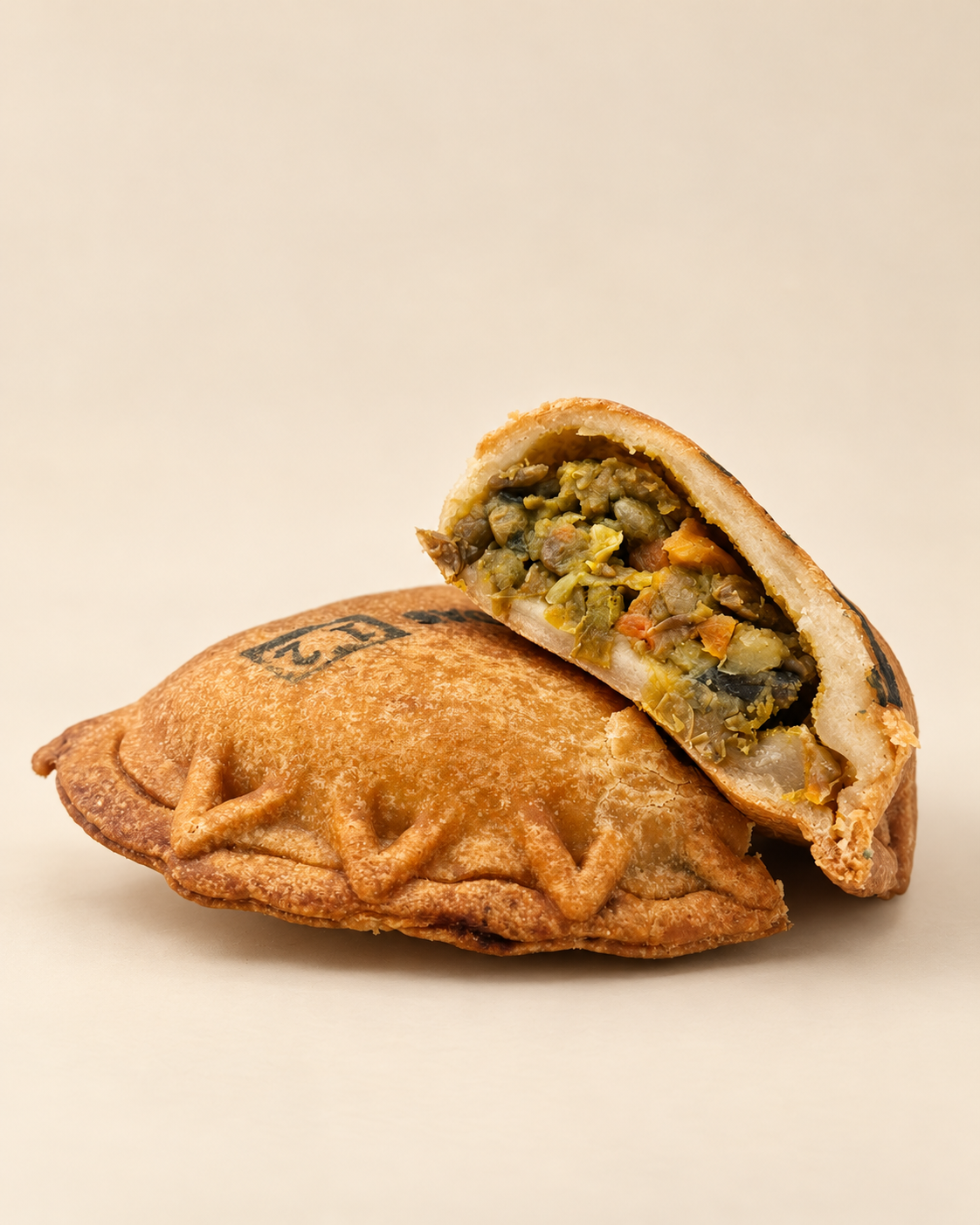 A savory pastry with a filling of vegetables and meat on decorative paper.
