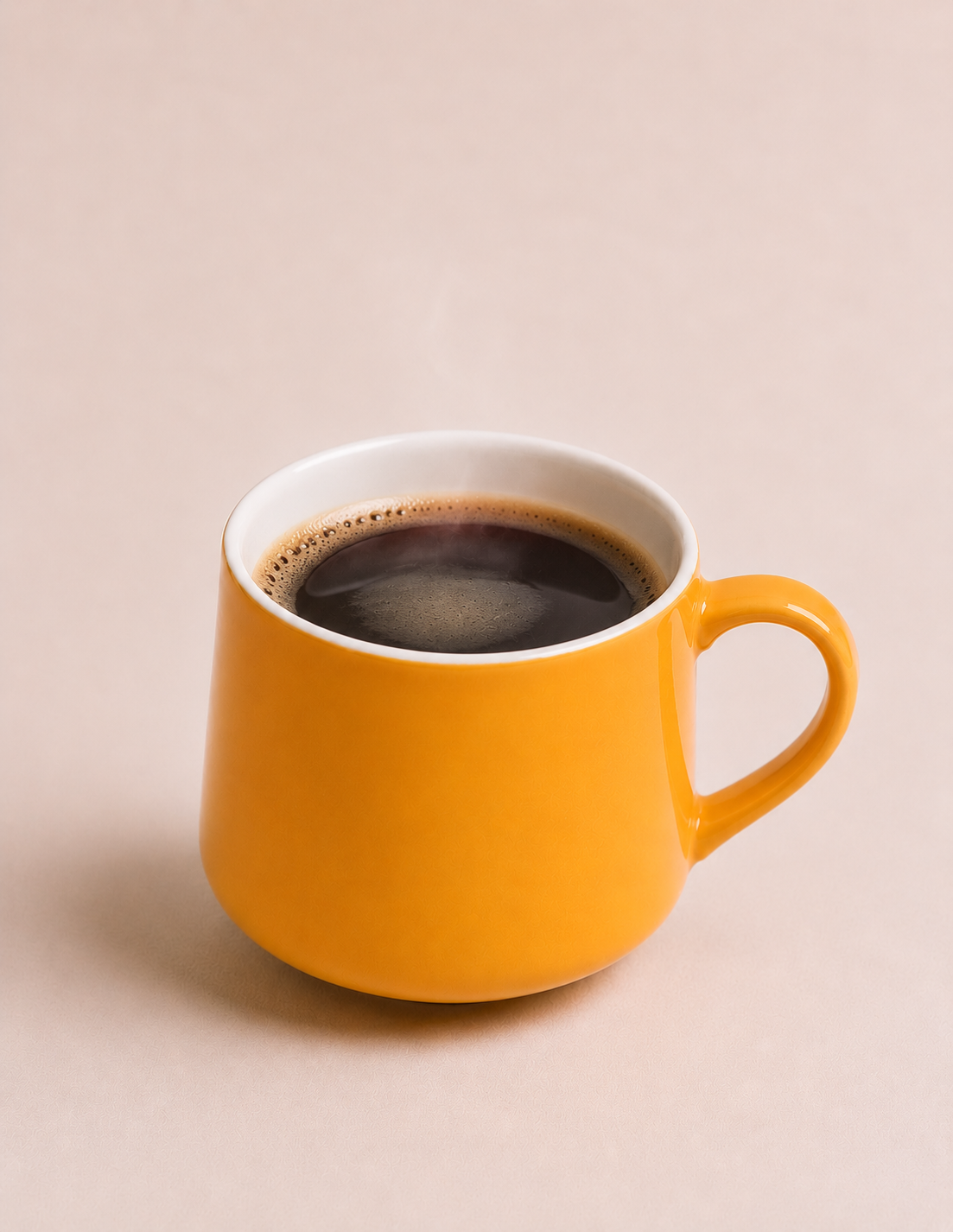 Yellow mug filled with black coffee on a light background.