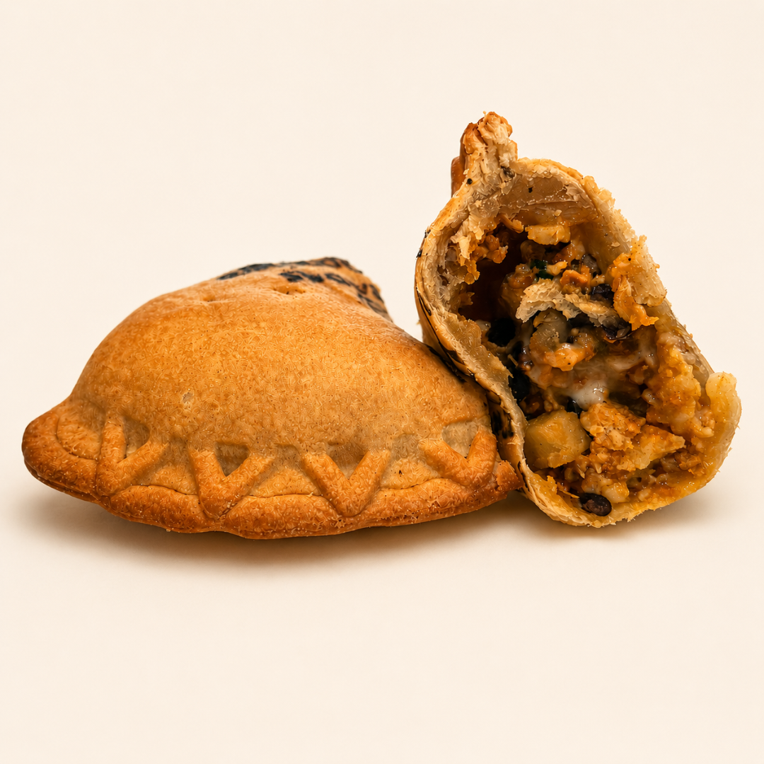 Empanada with a textured dough exterior and a filling of vegetables and ground beef, including black beans and peppers, on a patterned paper background.