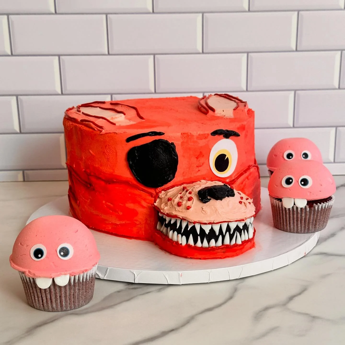 Five nights at Freddy&rsquo;s inspired lemon cake (I&rsquo;ve learned this is Foxy) along with some mutant red velvet cupcakes. We went with mostly frosting for this cake instead of fondant. Eyes are custom edible images and teeth are gum paste. 

#t