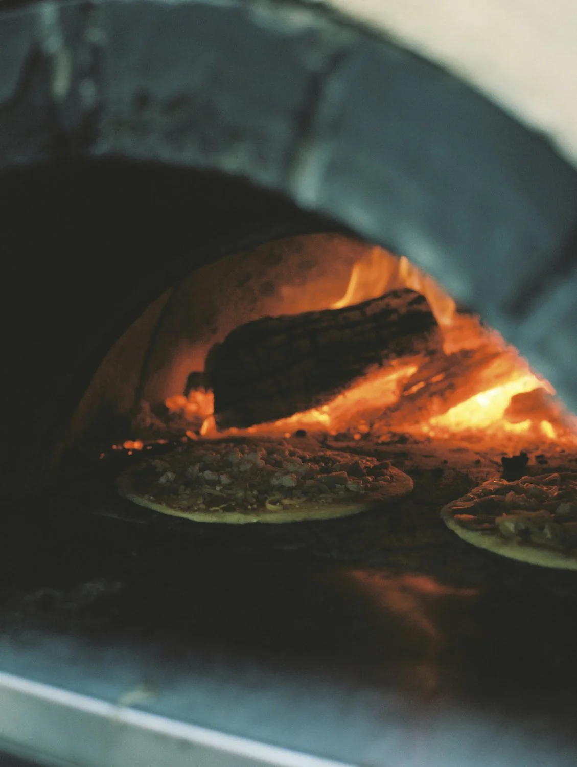Pizza baking in an oven with flames visible