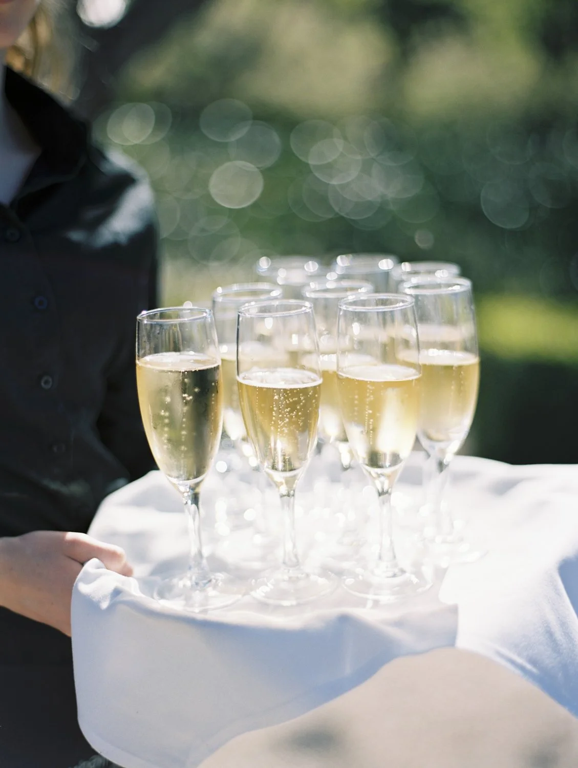 Tray of champagne glasses filled with sparkling wine outdoors