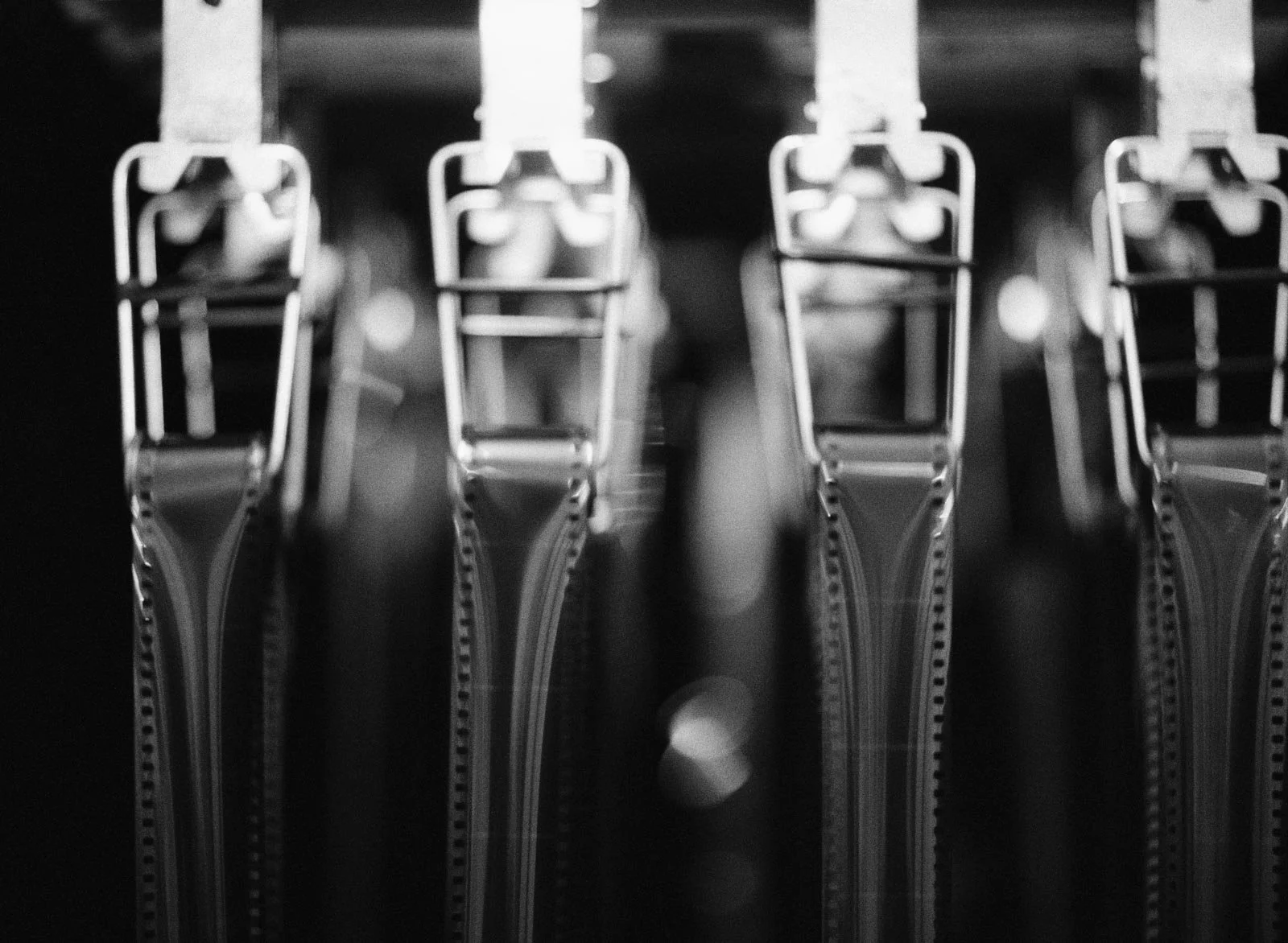 Close-up of multiple zipper pulls lined up vertically, in a black-and-white photograph.