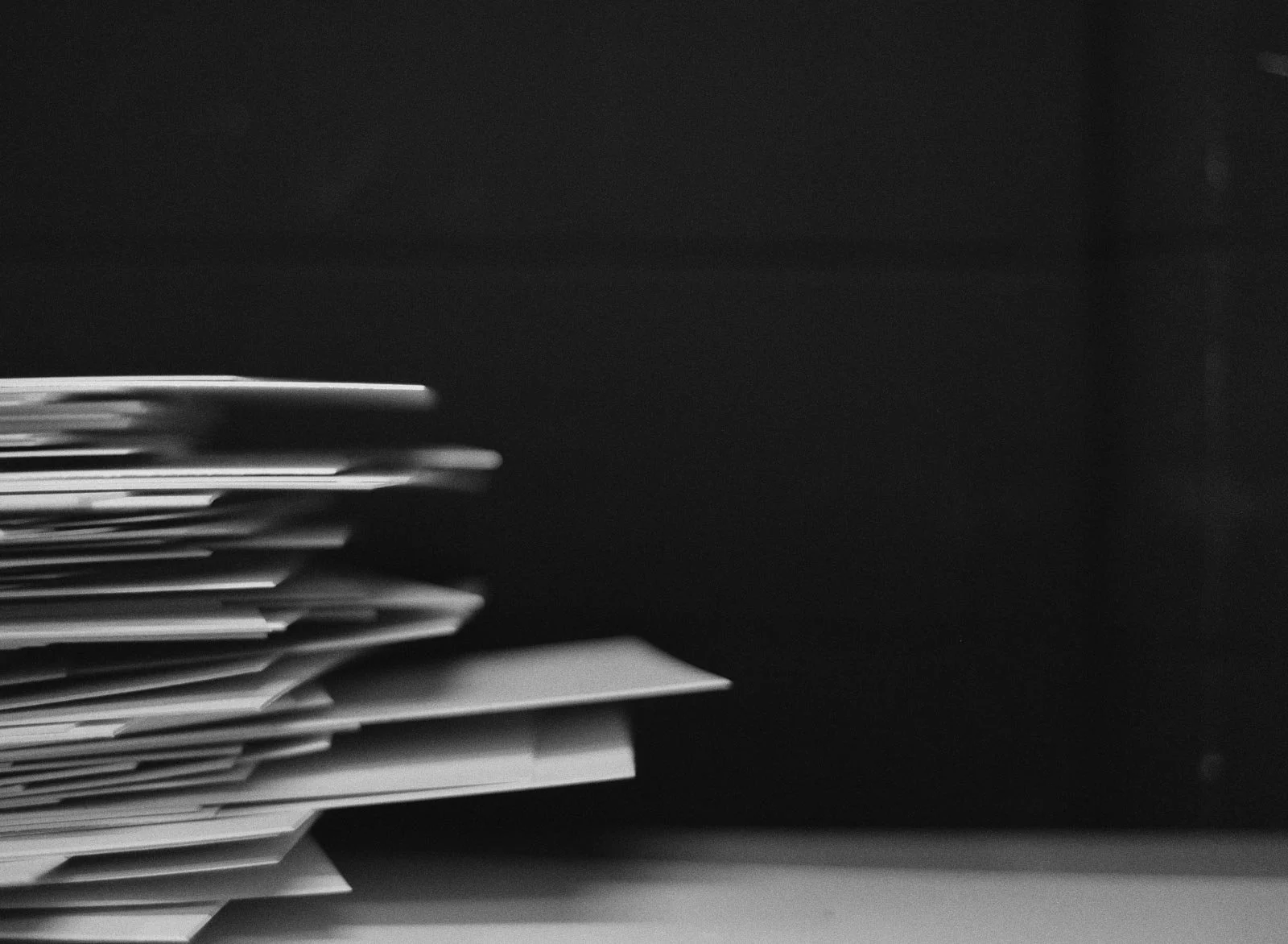 Stack of letters or documents on a surface with a dark background.