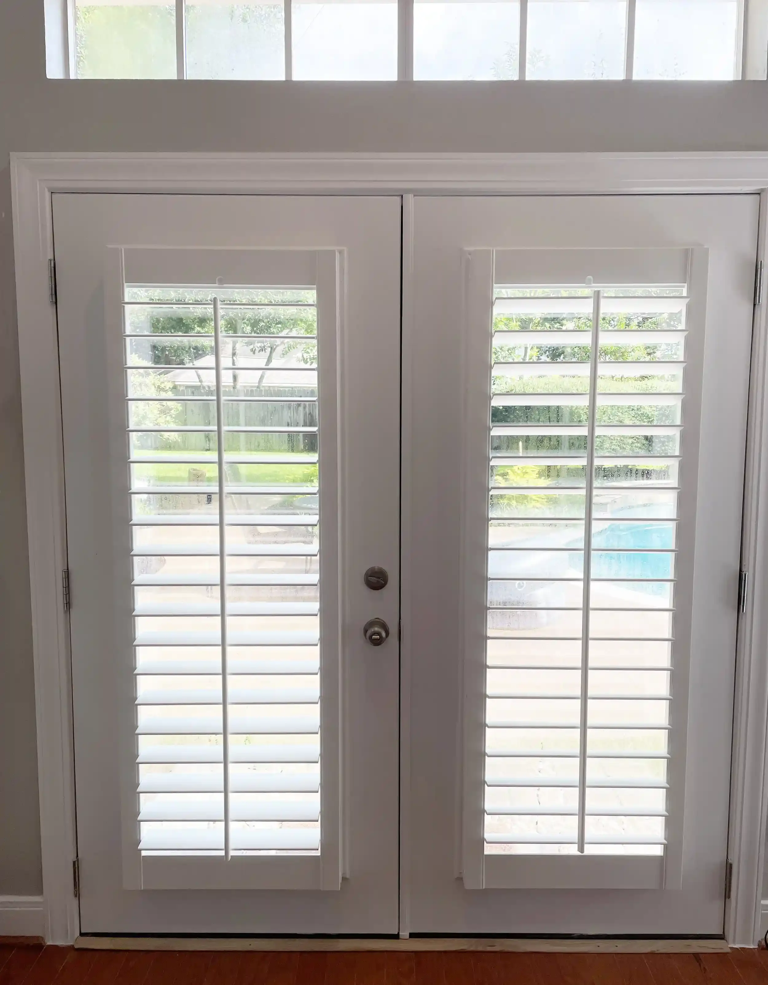 2 shutters mounted on French doors with a tilt bar