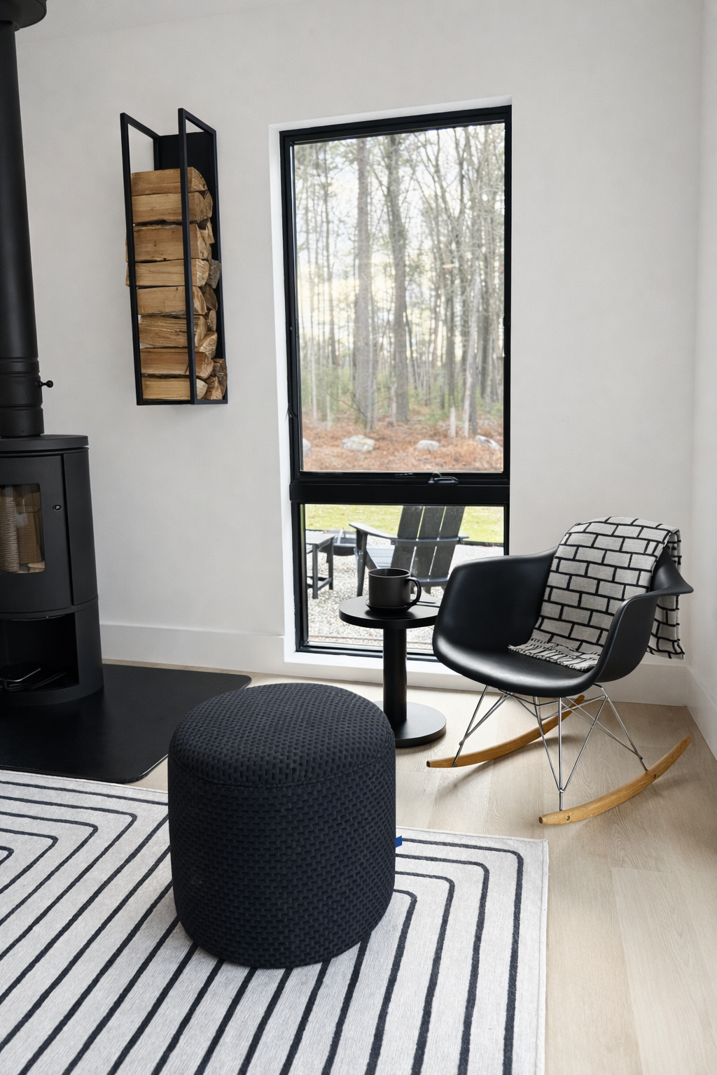 Modern living room corner with a black rocking chair, patterned throw, small round black side table - Perfect for coffee and a book ! 