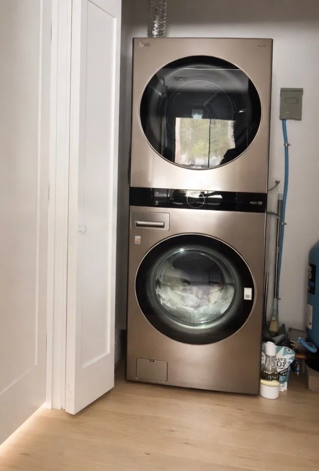 A stacked laundry washer and dryer in a laundry room, with the washing machine on the bottom and the dryer on top.
