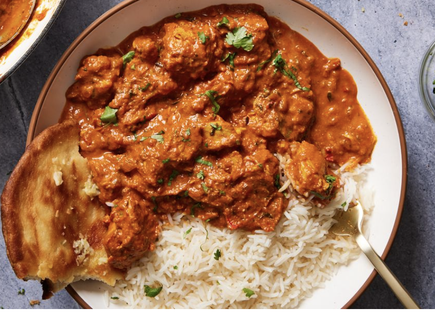 Plate of Indian curry with rice and naan bread garnished with cilantro.