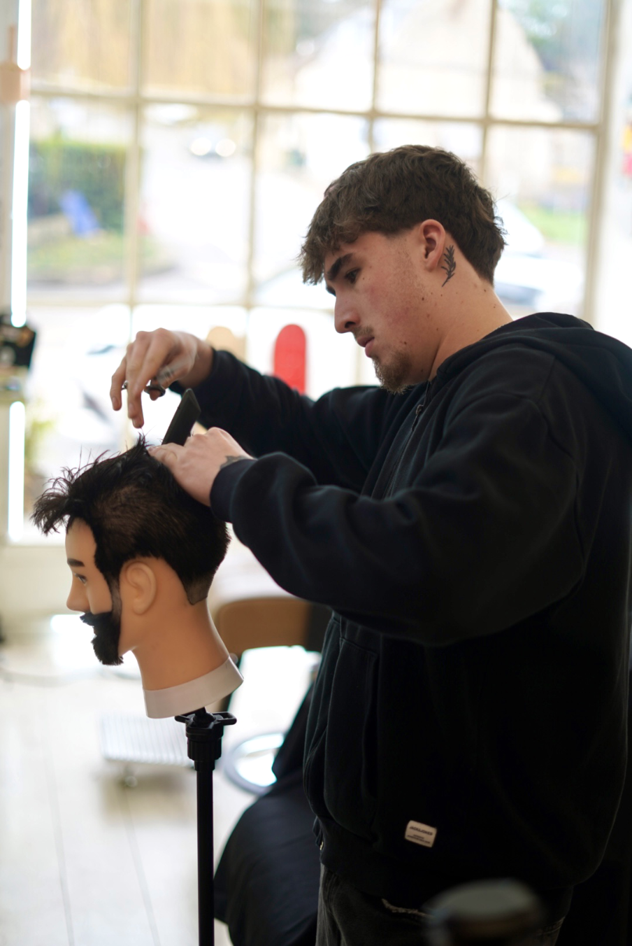 Ironworks Barbers' Full Barber, Tom, refining his skills with a mannequin head.