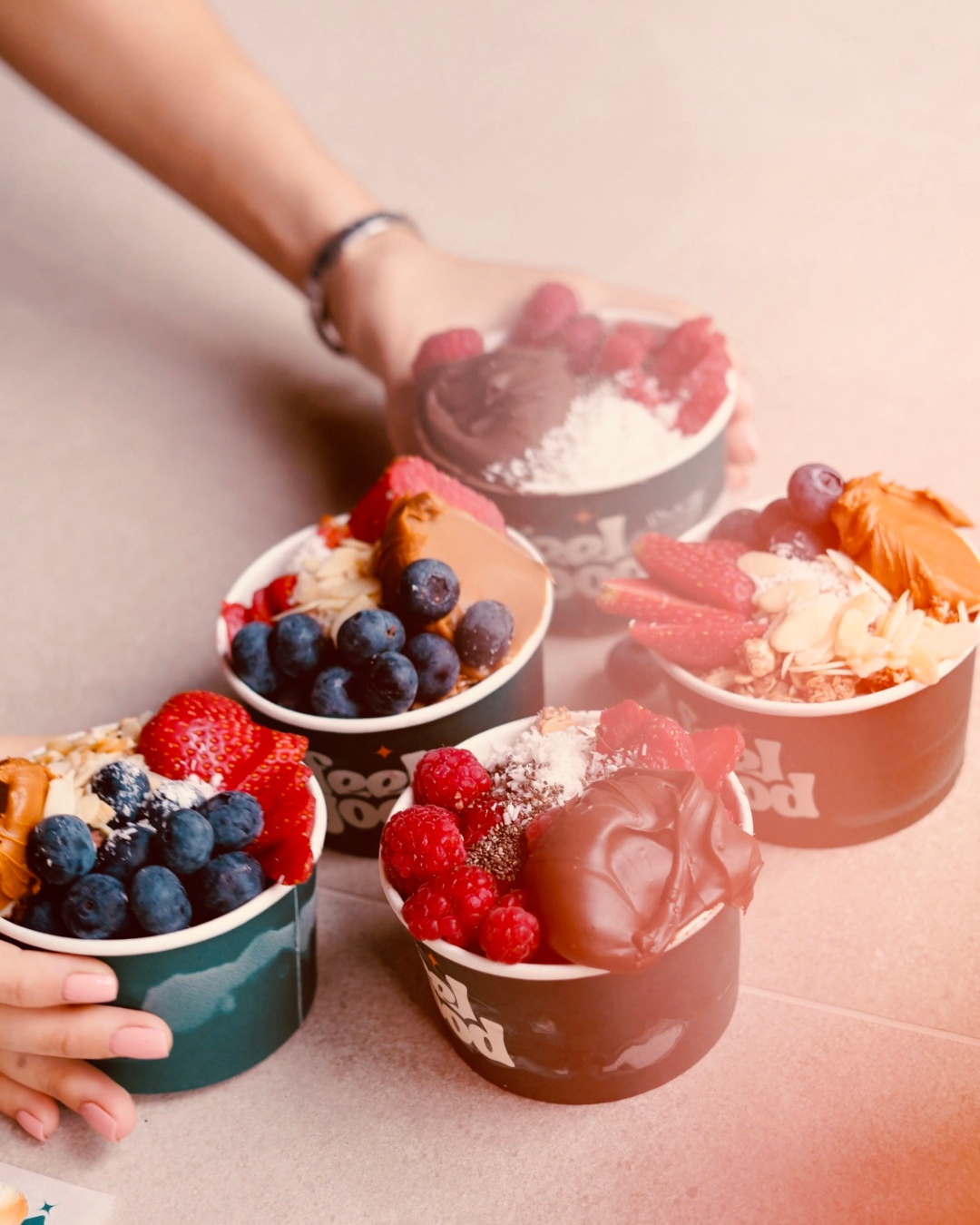 Several cups of frozen yogurt topped with fresh berries and other toppings on a table.