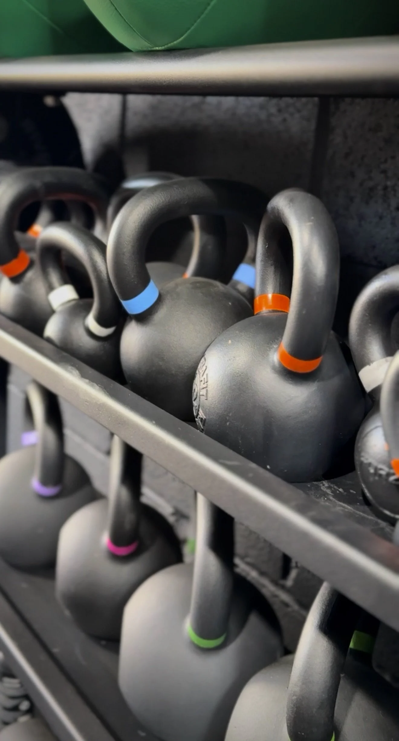 Shelf with multiple kettlebells with colored rings.