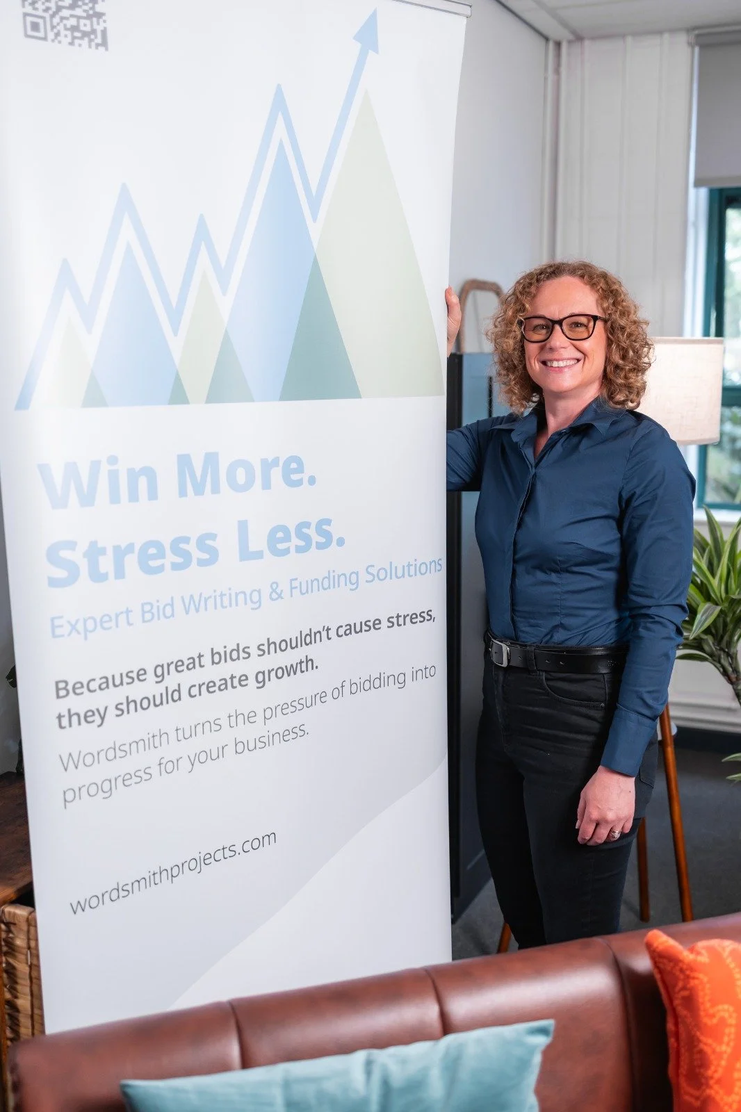 Image of Joanne Tryner at a business conference proudly standing by Wordsmith Projects' POS advertising