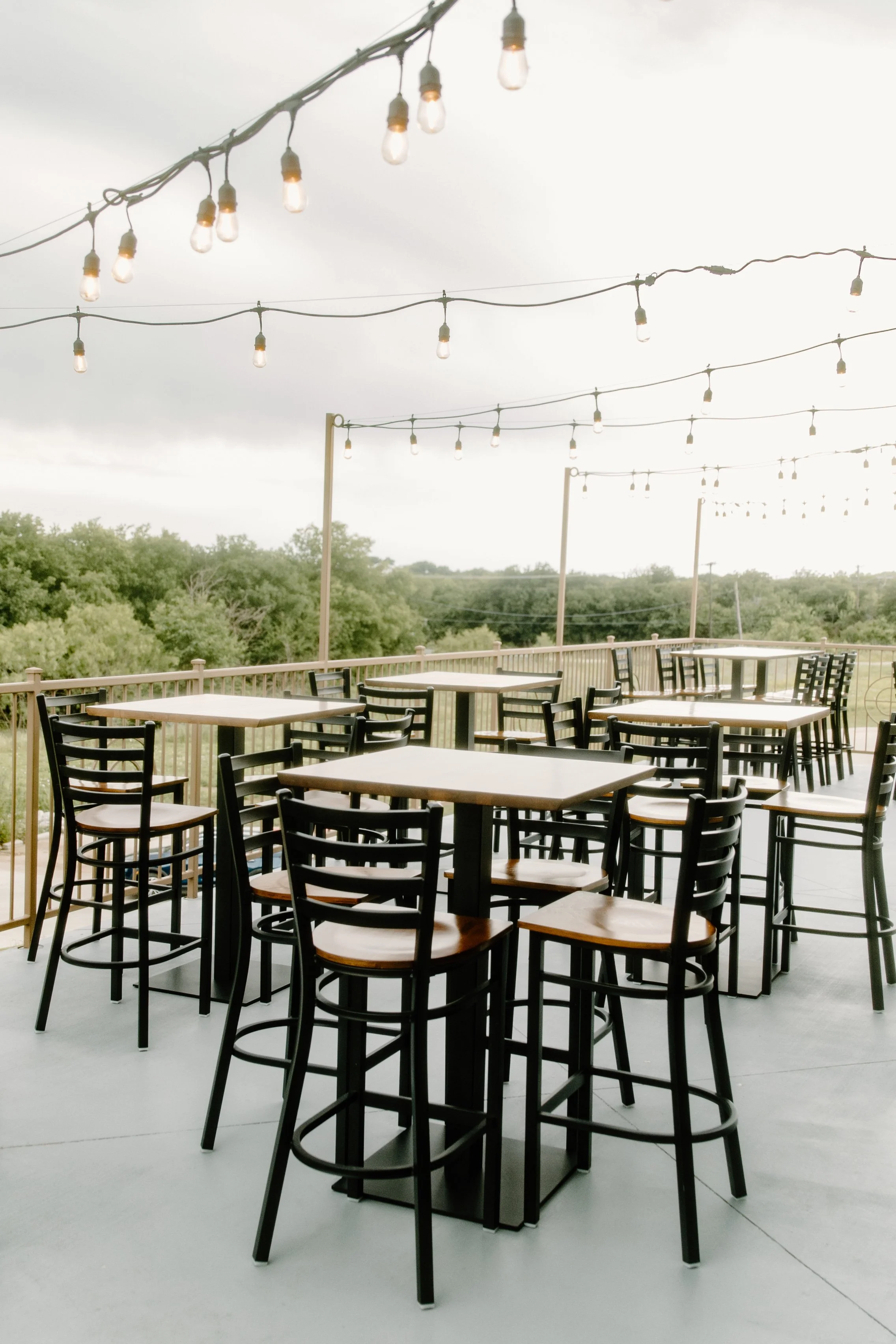 Outdoor patio with high-top seating and string lights at The Grand View Mansfield event venue