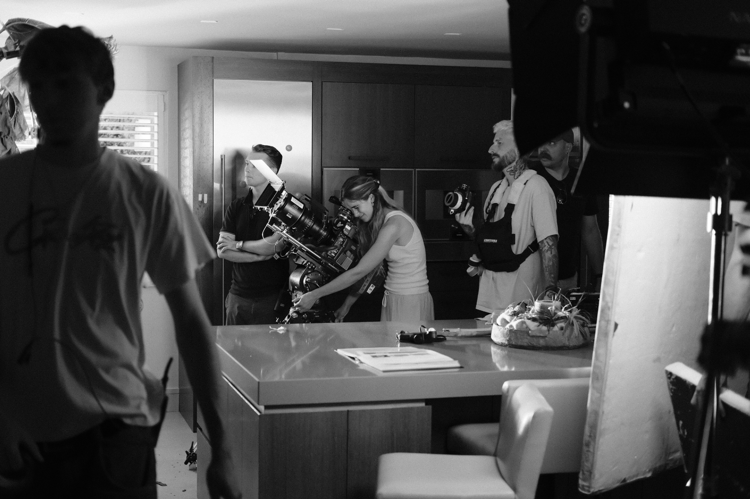 Film crew preparing equipment on set in a modern kitchen interior