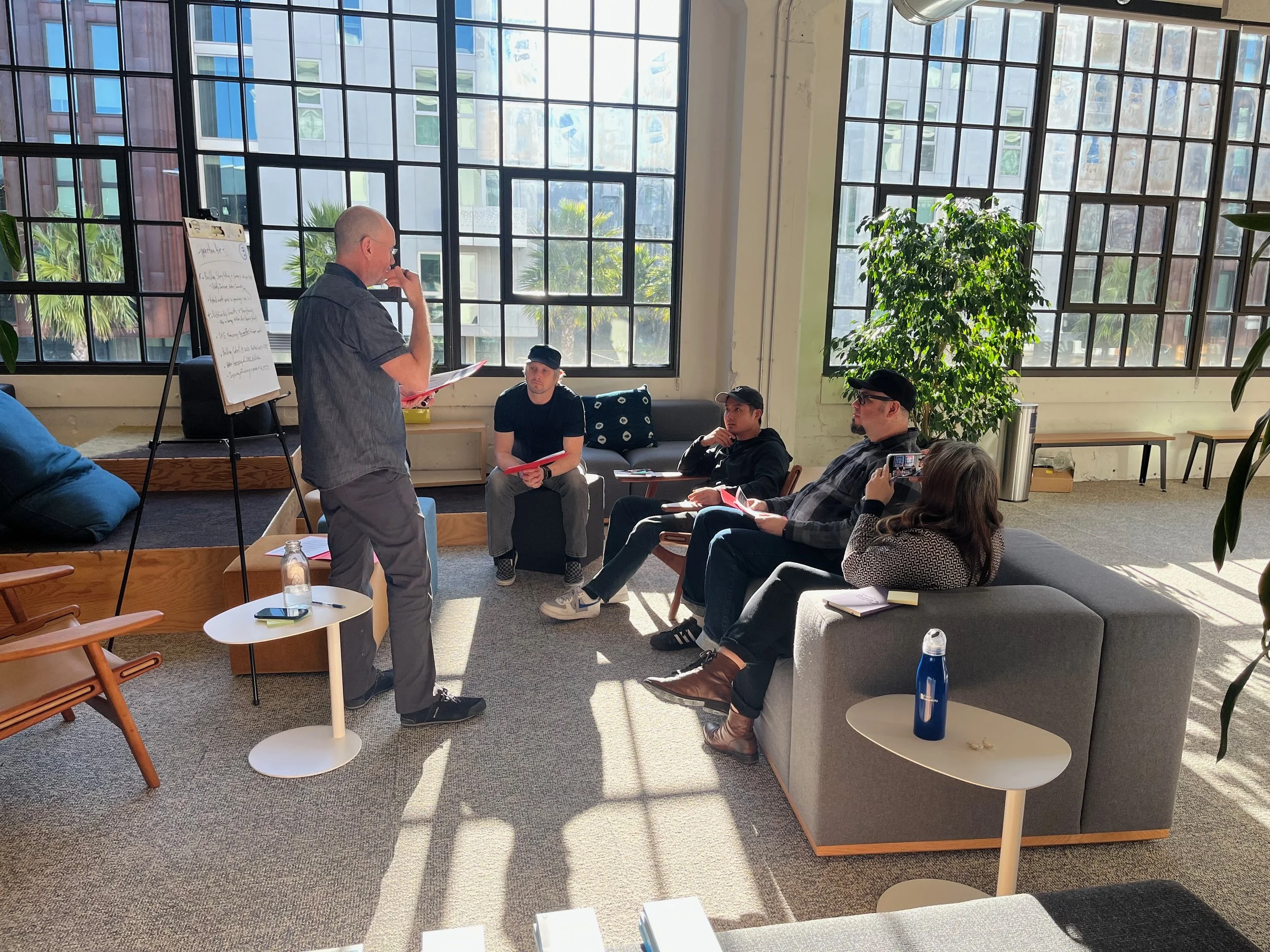 Team member sharing a story at a flip chart while colleagues listen in a bright loft workshop space