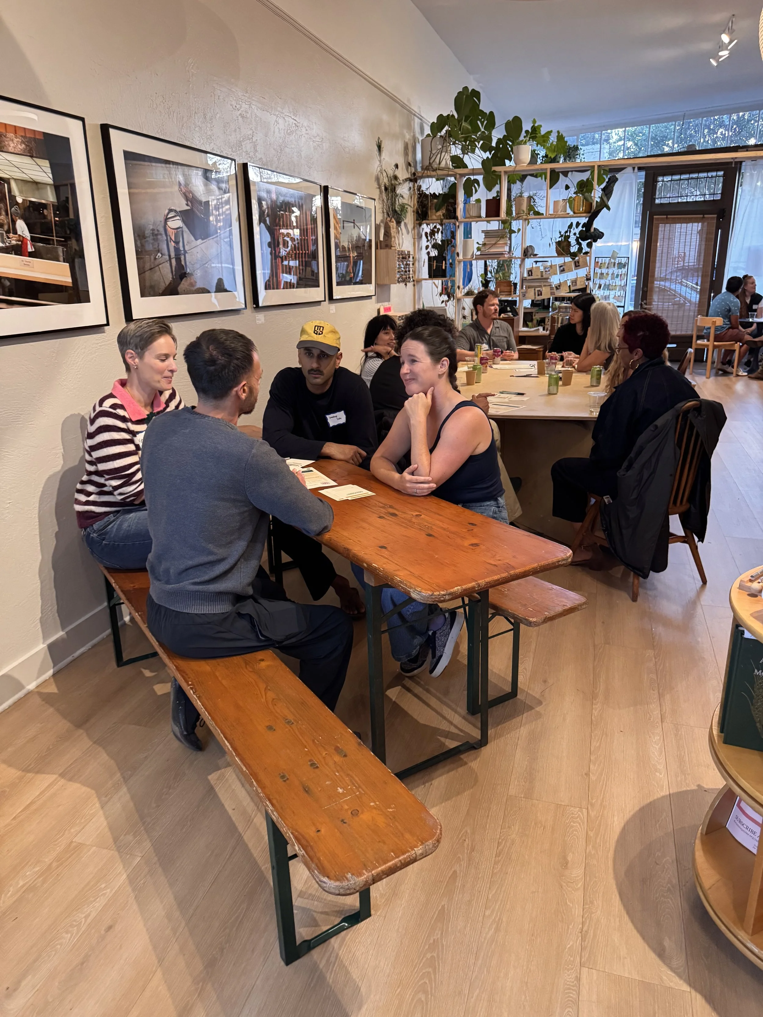 People in pairs trading stories across long wooden tables at an in-person story event