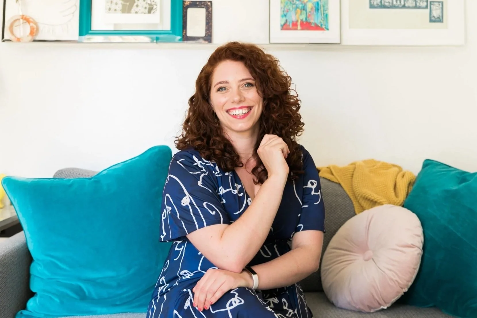 Liz Morrison, Berkeley Story Coach, sitting on a teal couch