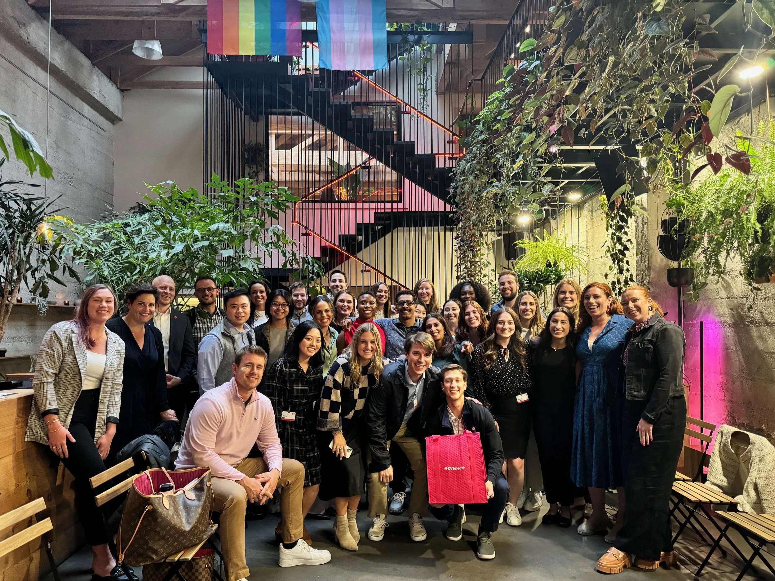 Large corporate team group photo after a leadership storytelling workshop in a plant-filled atrium