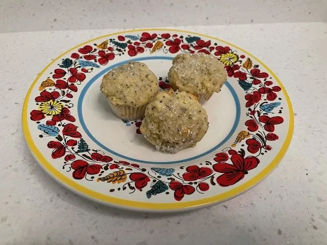 Three lemon poppyseed muffins on a brightly colored plate.