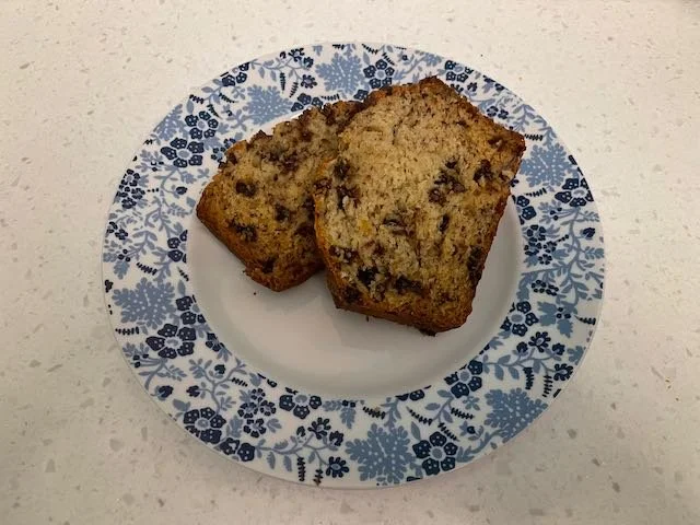 Two slices of banana bread with chocolate chips on a plate with blue floral border.