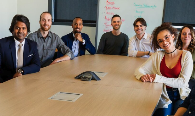 Six Interpreters sitting around a conference table in a meeting room, smiling at the camera.
