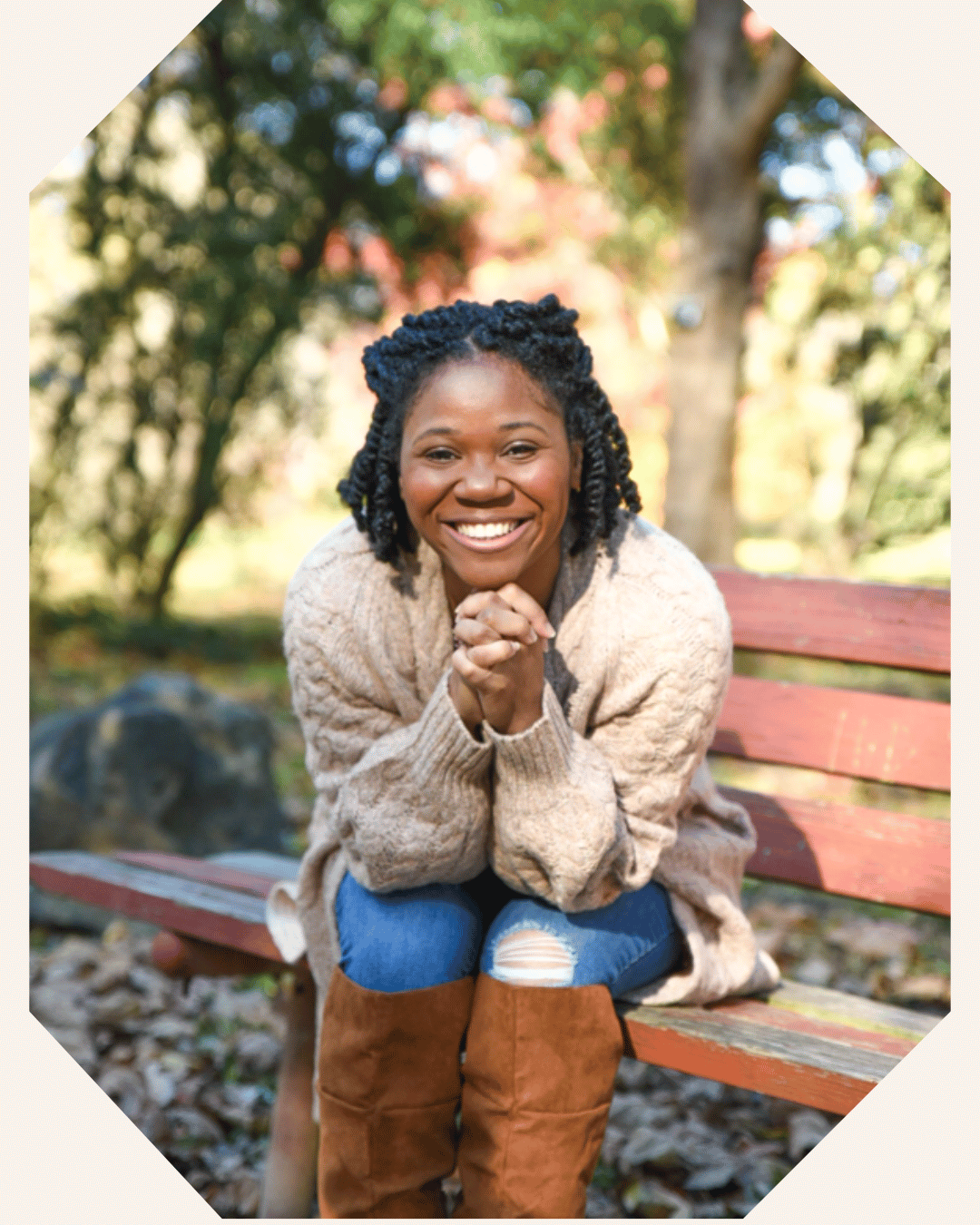 Author Dionna Tillery sits on a park bench and leans toward the camera with a big smile on her face.
