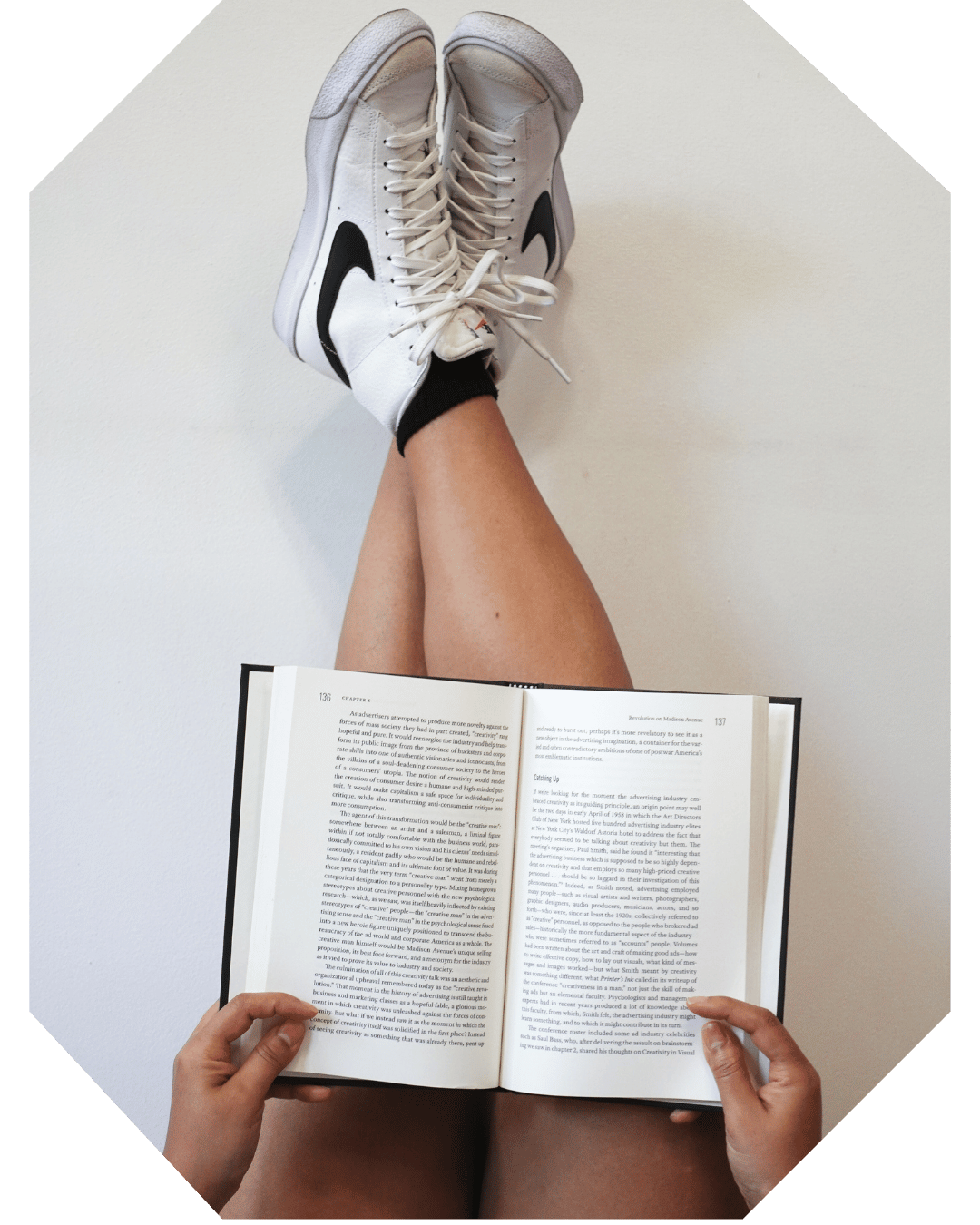 Book Coach Sabrina kicks back with her legs and feet up on the wall while reading a book.