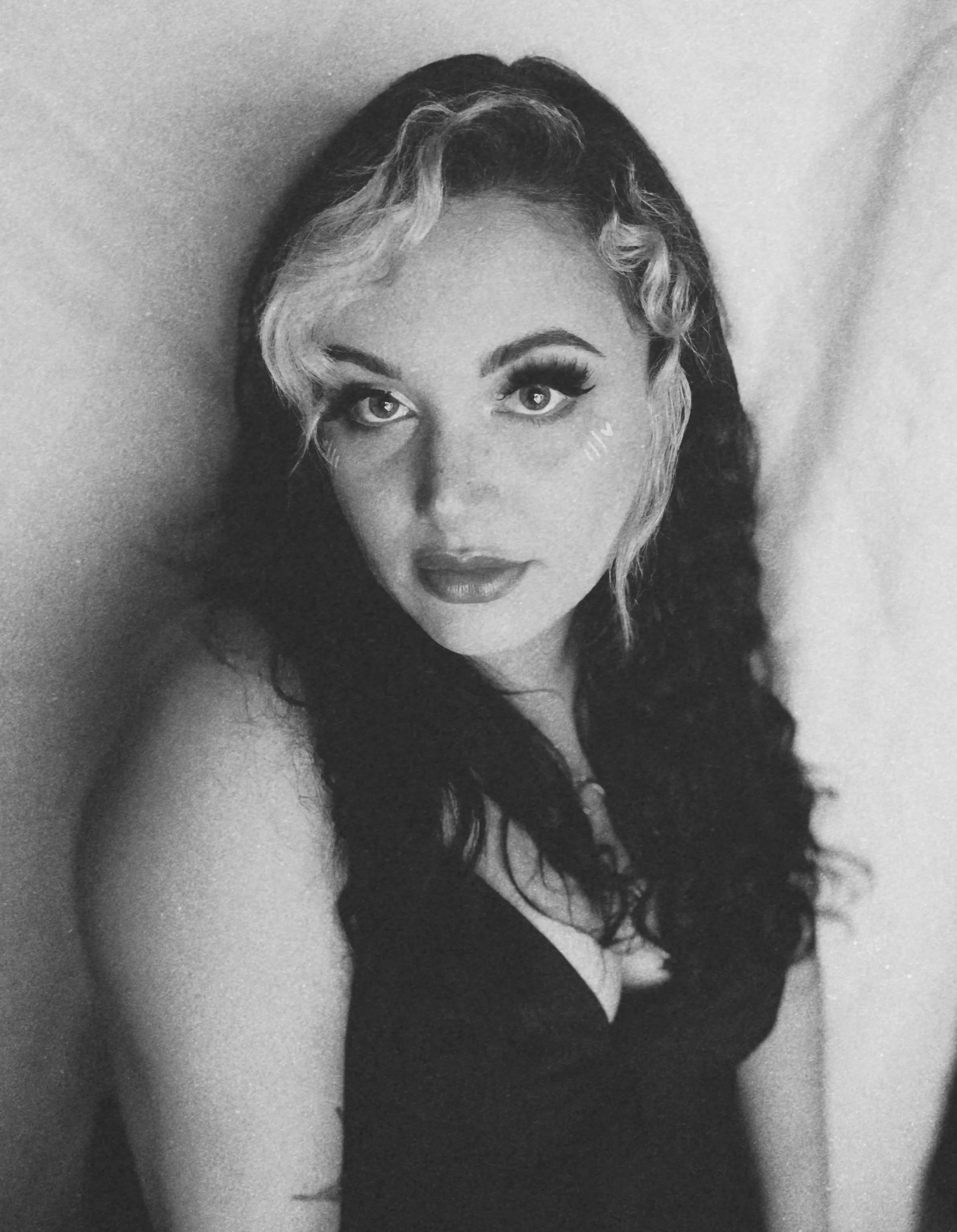 Black and white close-up portrait of Jasmin of Jasmin Sullivan Photography with long wavy hair, makeup, and a confident expression.