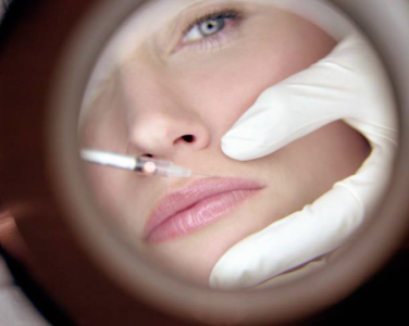 A woman receiving a facial injection from a medical professional wearing gloves.