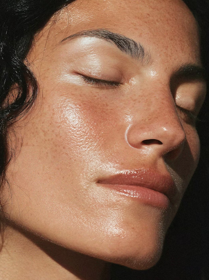 A woman floating on her back in a swimming pool, smiling with her eyes closed and her face wet.