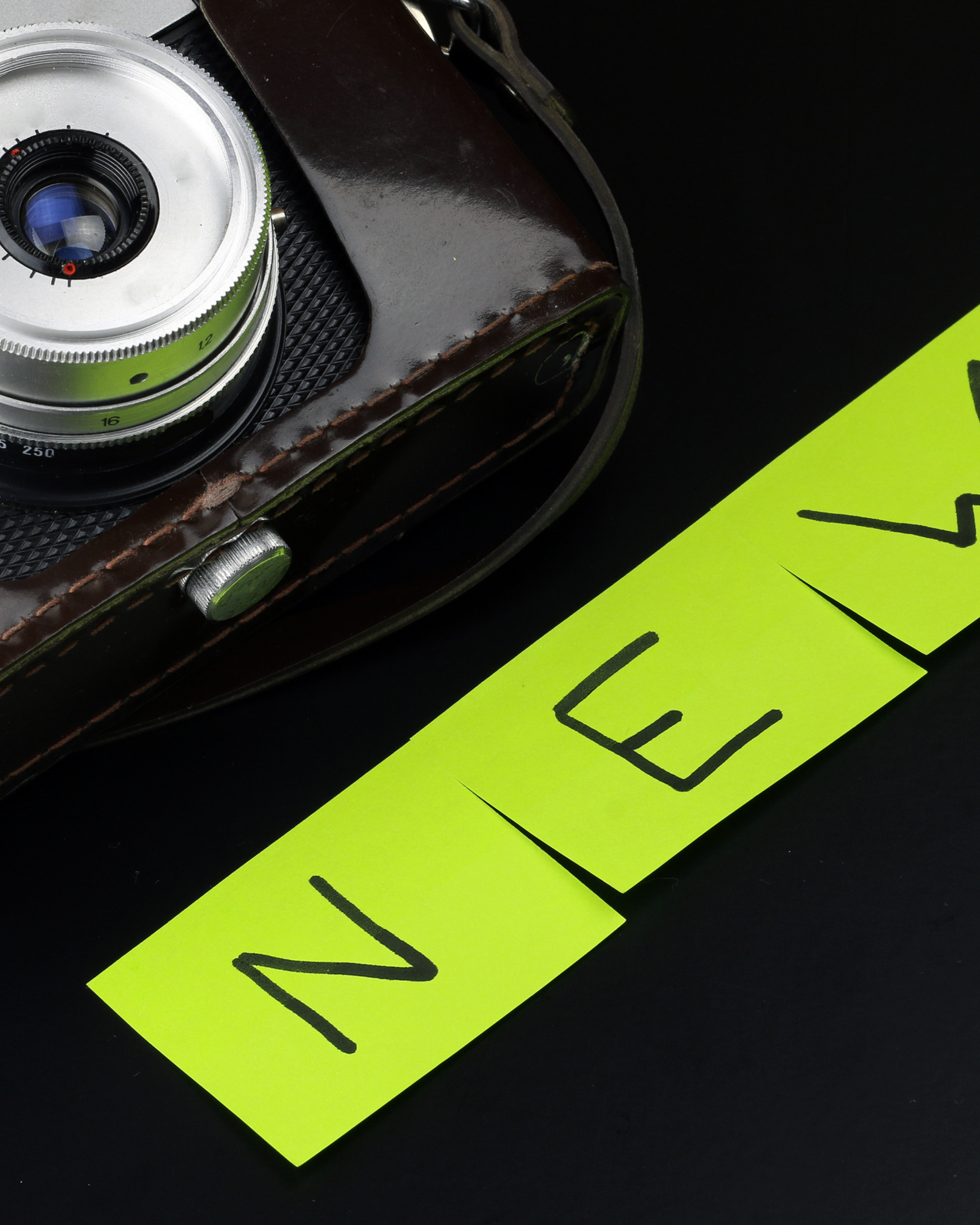 Close-up of a vintage camera with a bright yellow sticker with black writing on a black background.
