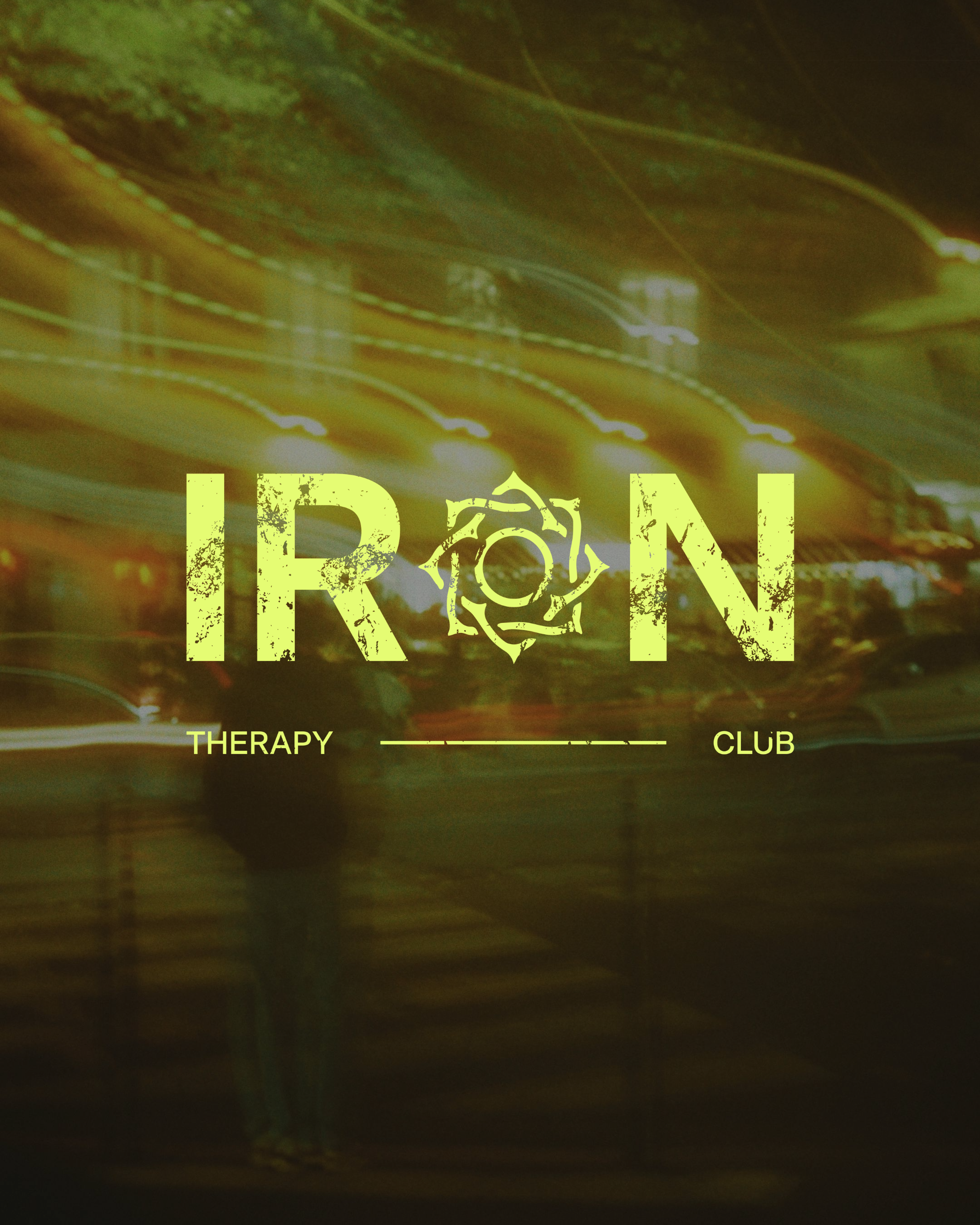 The image shows a neon sign of the word 'IRÓN' with a stylized iron symbol in between, in a dimly lit environment with greenish-yellow hues and reflections.