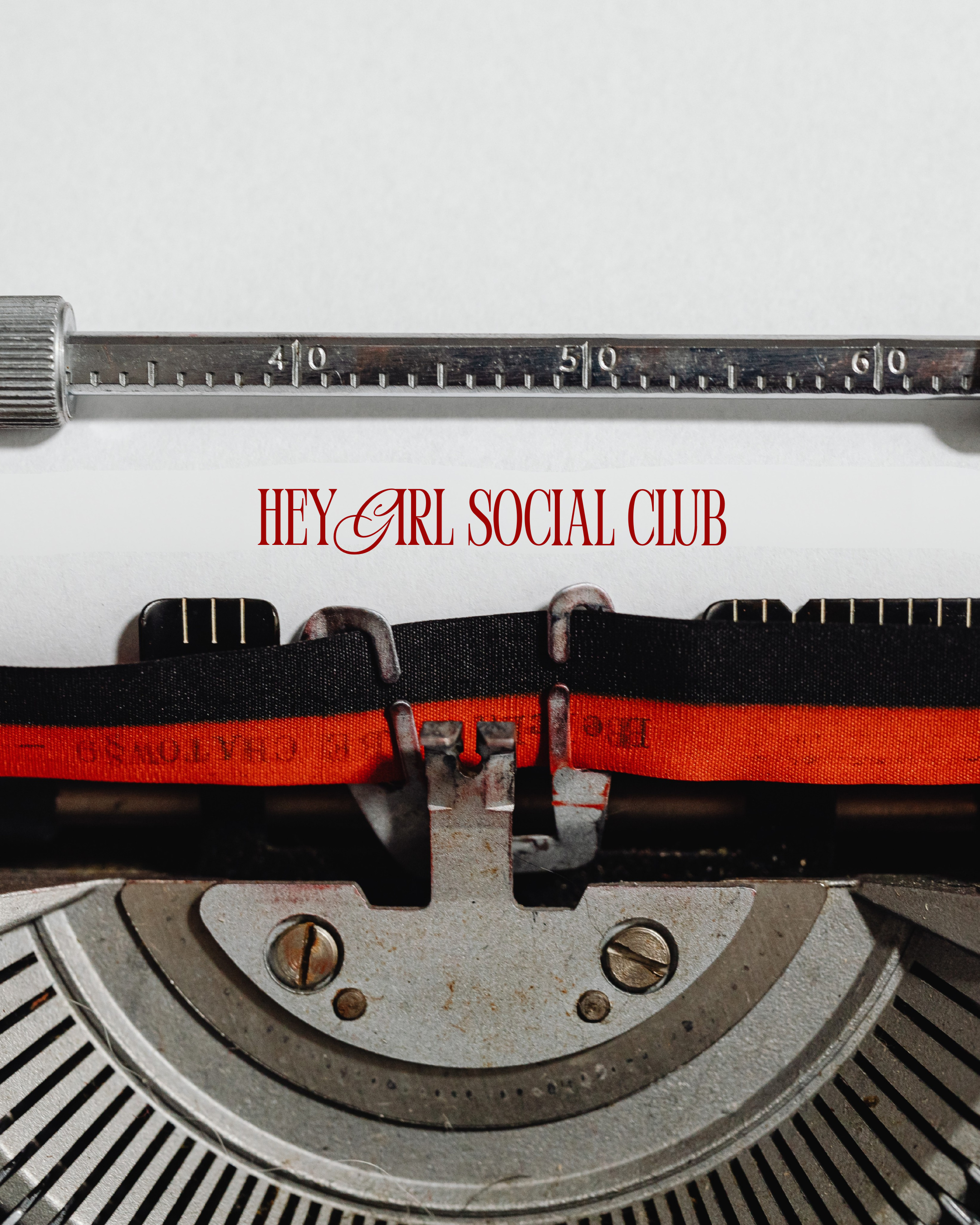 Close-up of a typewriter's inner mechanism showing the roller and typebars, with a white background and text 'HEY GIRL SOCIAL CLUB' printed in red.