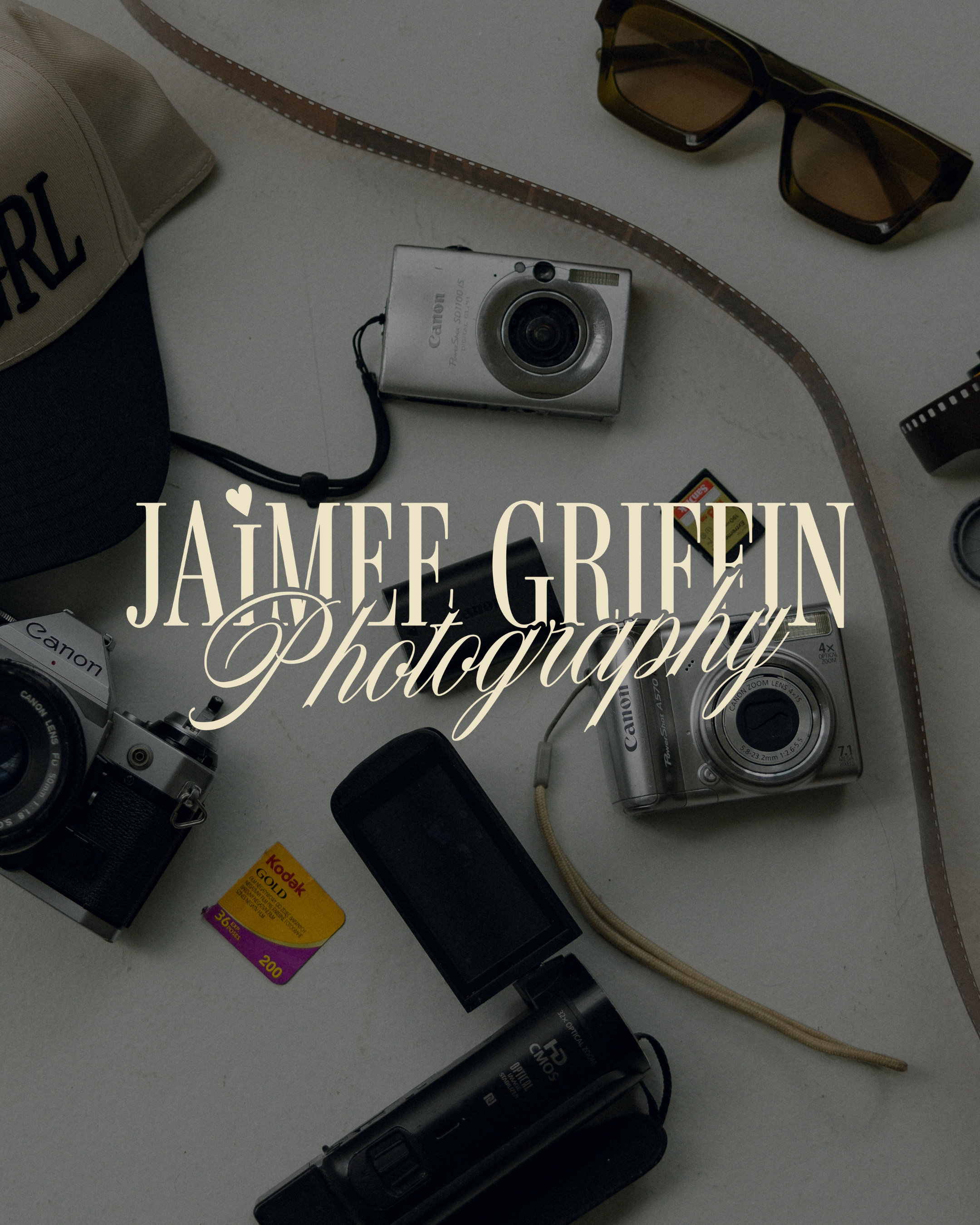 A collection of vintage cameras, sunglasses, a film strip, memory cards, and an electronic device on a white surface.