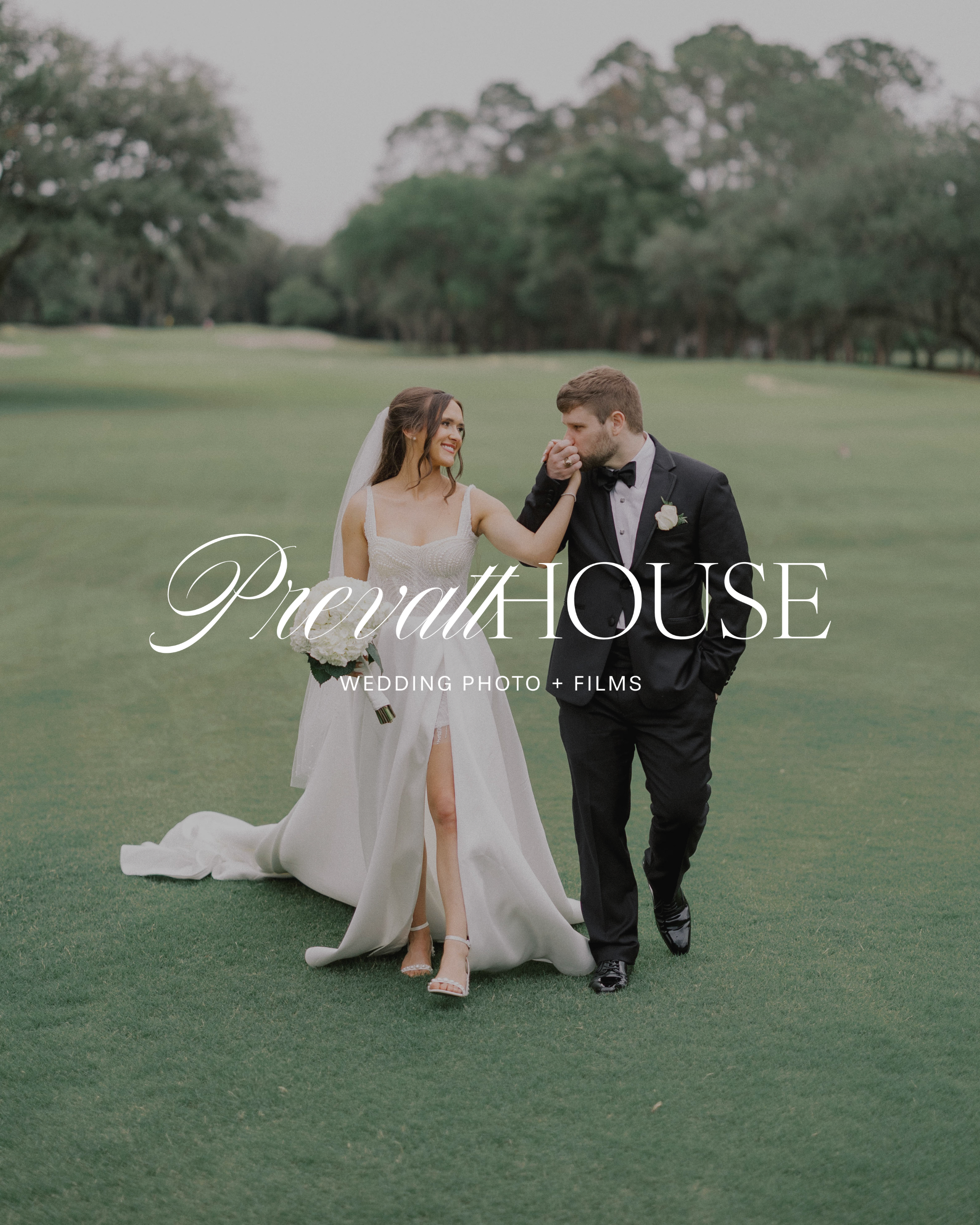 A bride and groom on a golf course, with the bride holding a bouquet and the groom kissing her hand.