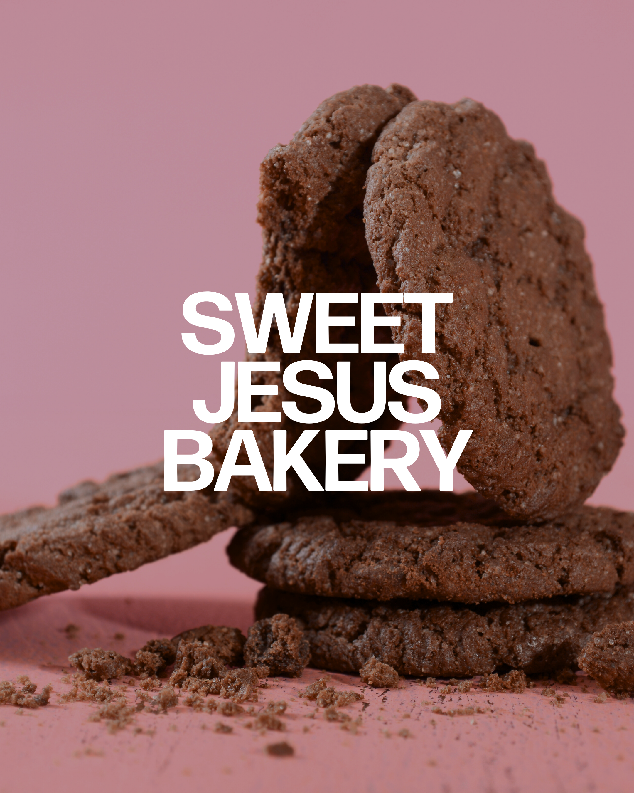 Close-up of chocolate cookies stacked and crumbled on a pink surface, with powder and crumbs scattered around.