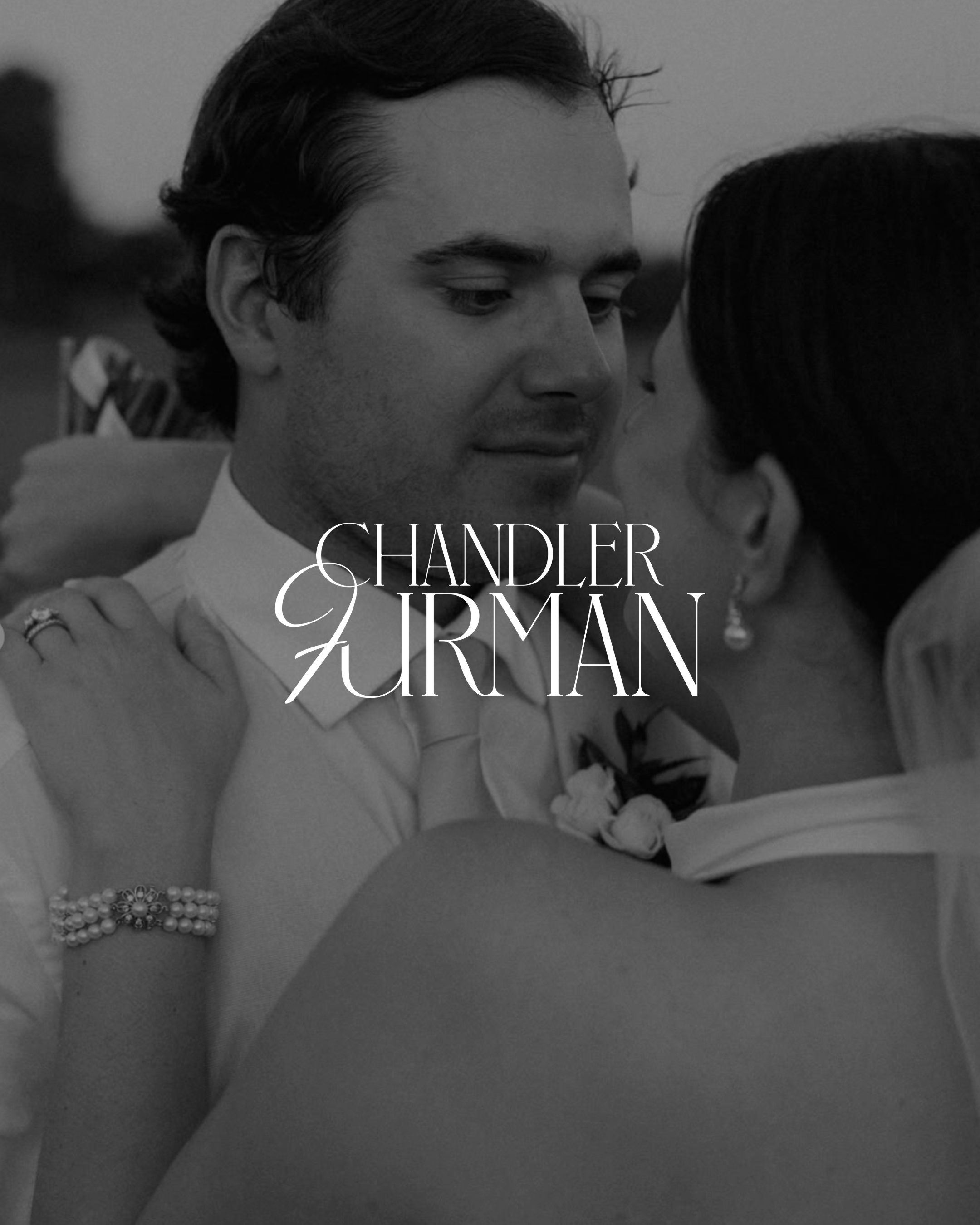 A black and white photo of a woman with pearls and bracelet, hugging a man dressed in a tuxedo, at a wedding or formal event.